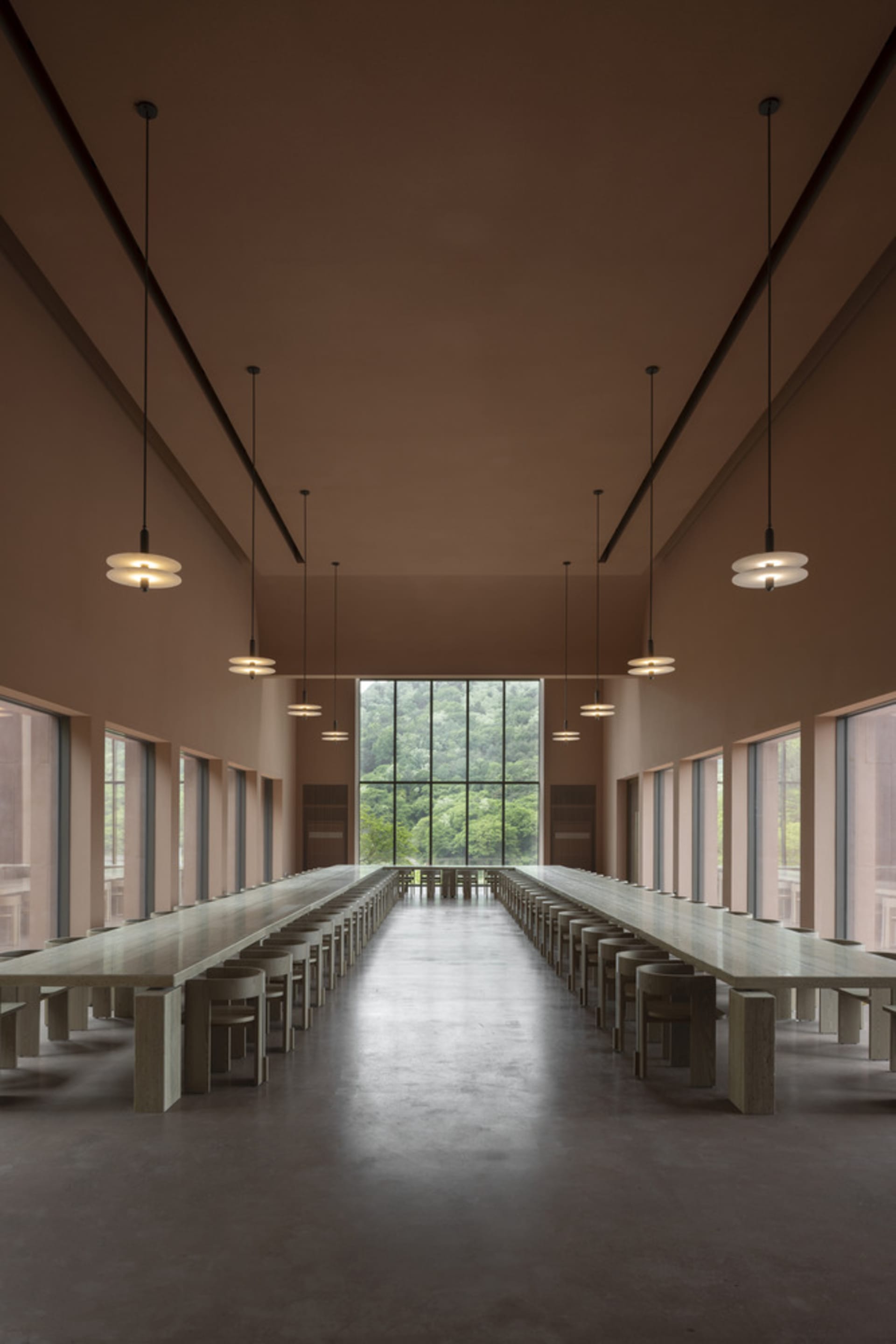 Spacious dining area with multiple long tables and chairs, well-lit by overhead lights or natural daylight