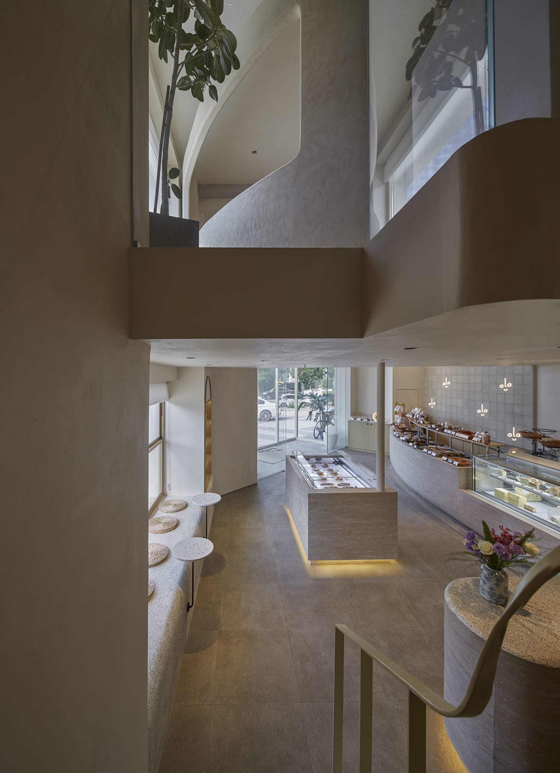 Open modern kitchen and dining area with natural light, a large window, a counter, sink, dining table, chairs, and potted plants