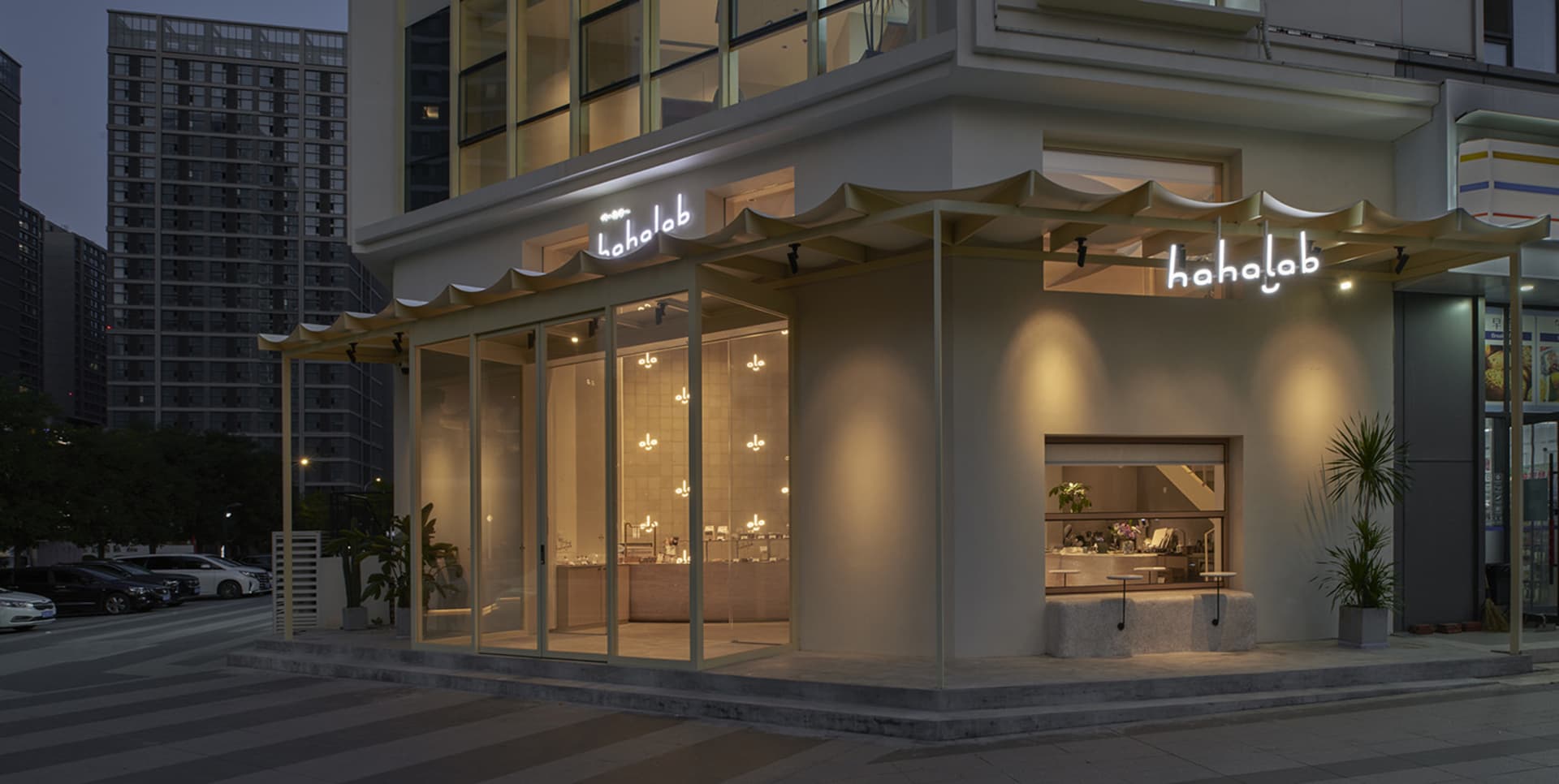 Well-lit retail space with white walls, glass windows, and potted plants, featuring comfortable seating areas