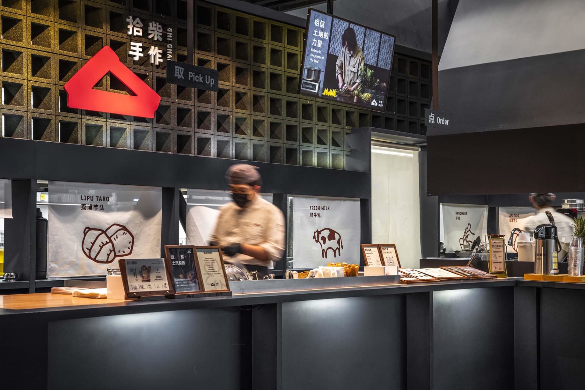 Casual Asian restaurant with a counter displaying food items, a TV on the wall, and two people in the scene