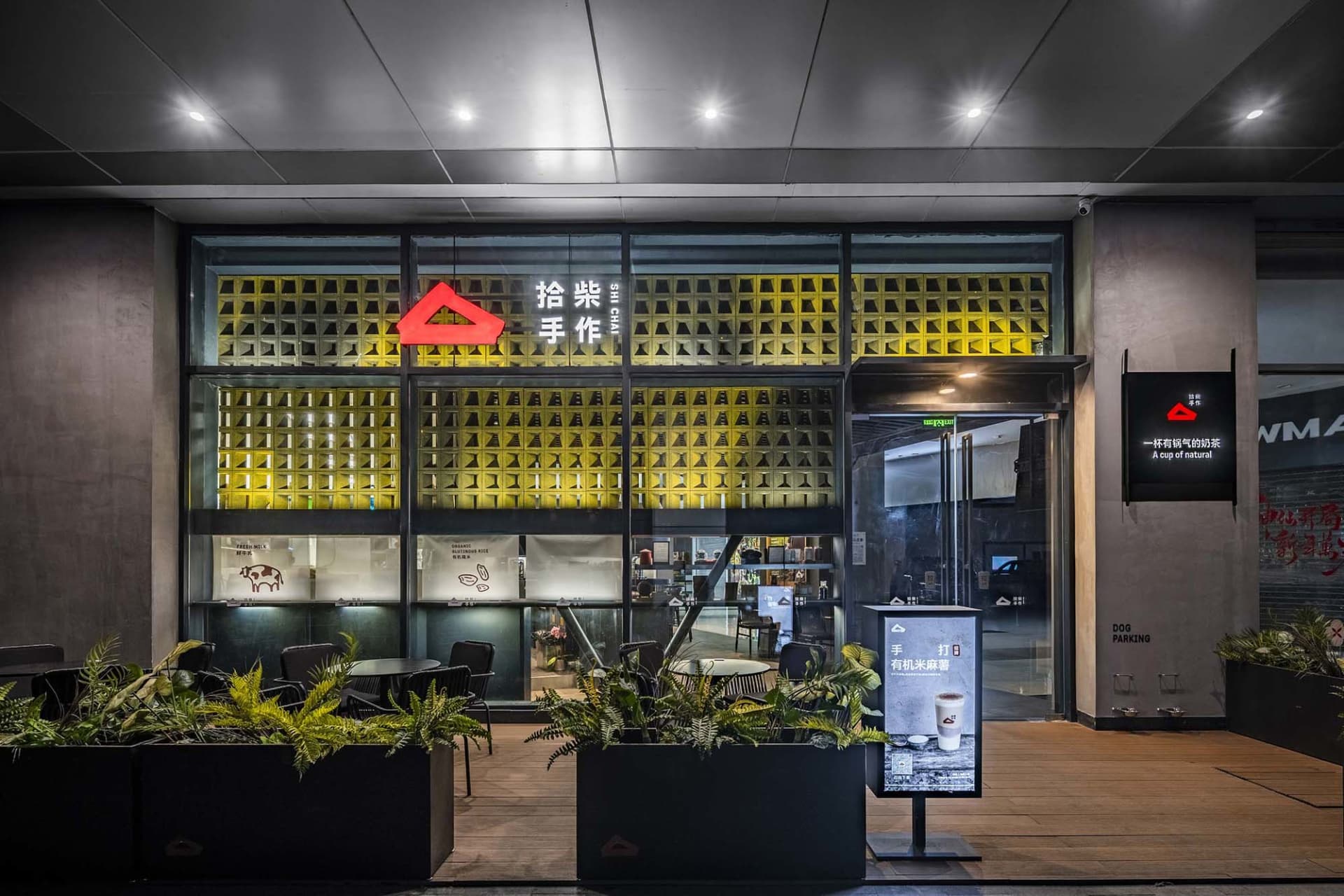 A modern coffee shop with a yellow theme, featuring a large window, chairs, a dining table, and decorative elements like potted plants and vases, creating a cozy and inviting atmosphere
