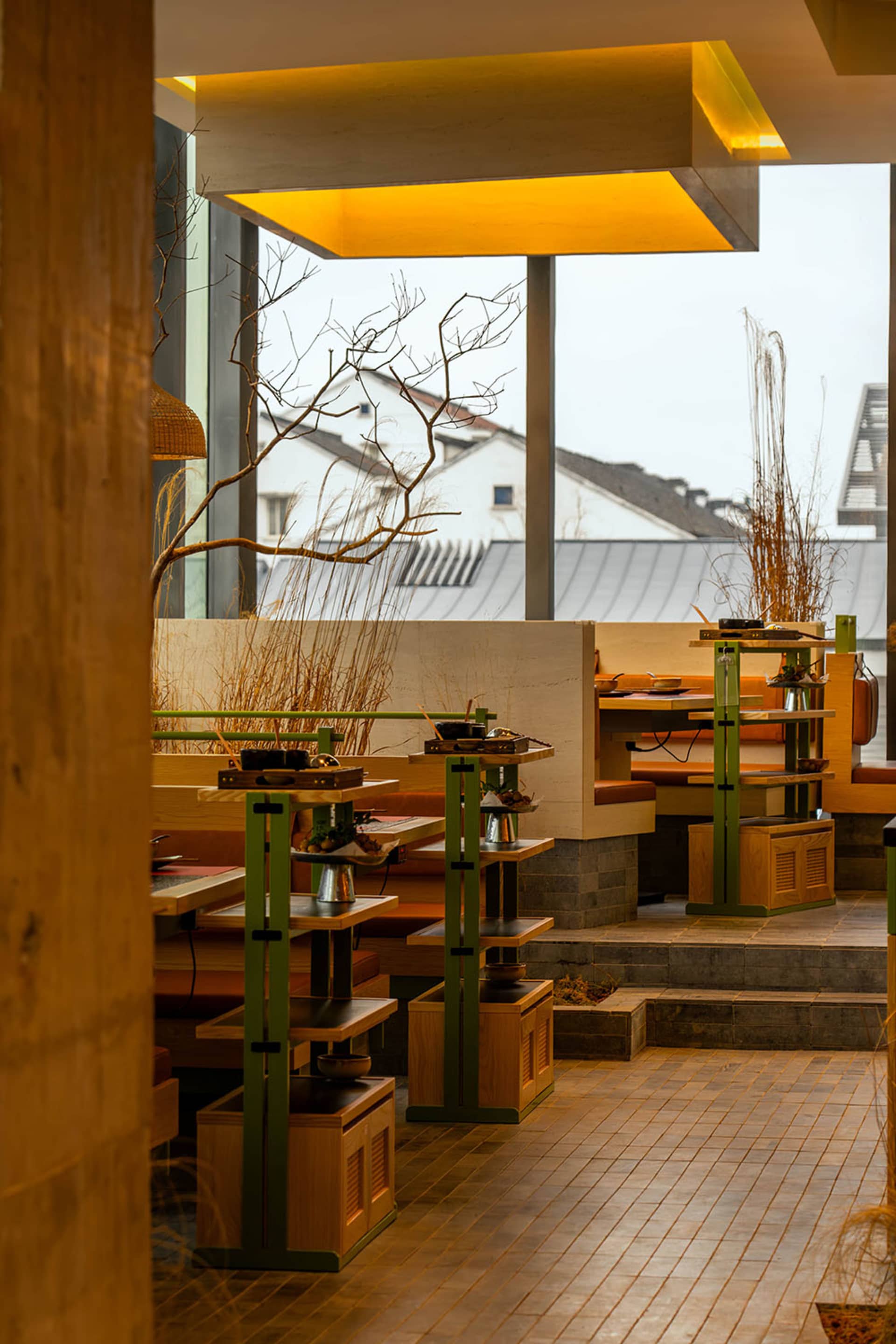 A modern restaurant interior with wooden tables and chairs, featuring a warm and inviting atmosphere with several dining tables and benches