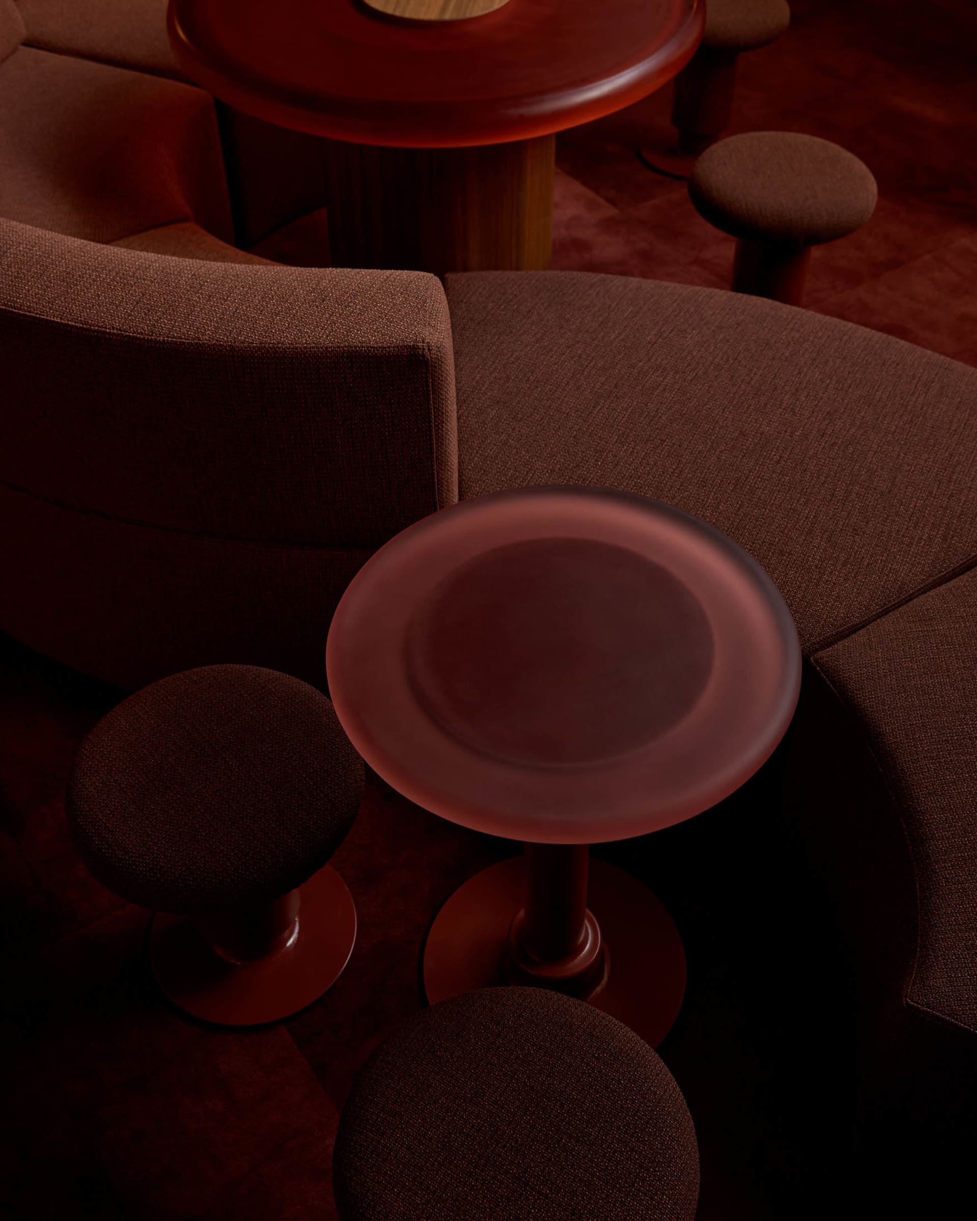 Cozy living space with brown and red tones, featuring two couches, two chairs, and three dining tables, creating a warm and inviting atmosphere