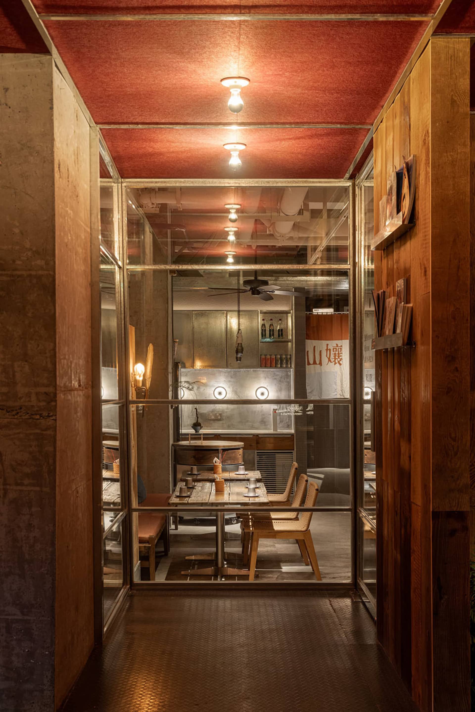 A cozy restaurant dining area with tables, chairs, and bottles, visible through a glass door