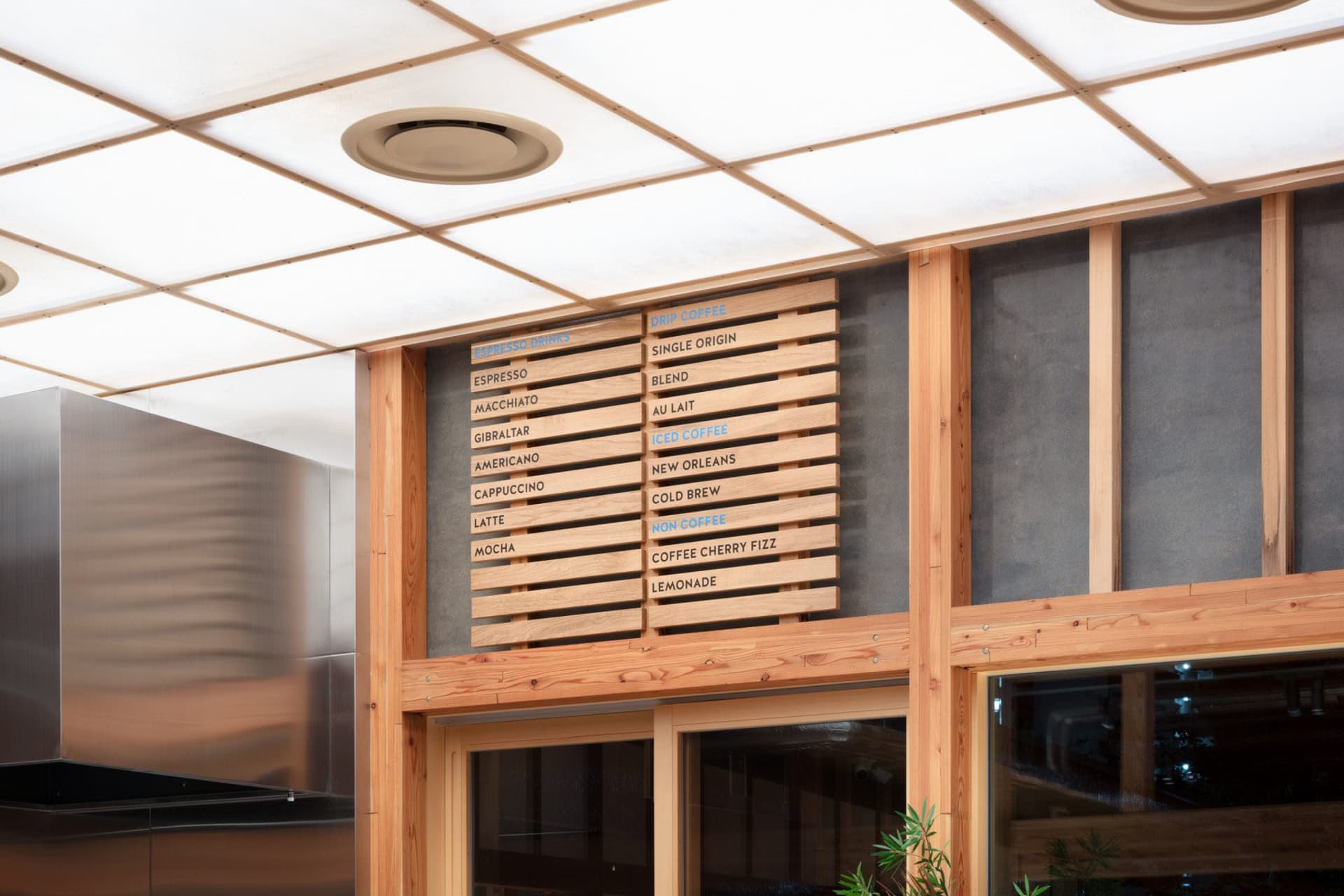 A restaurant interior with a wooden menu board, dining area, and potted plants creating a welcoming atmosphere