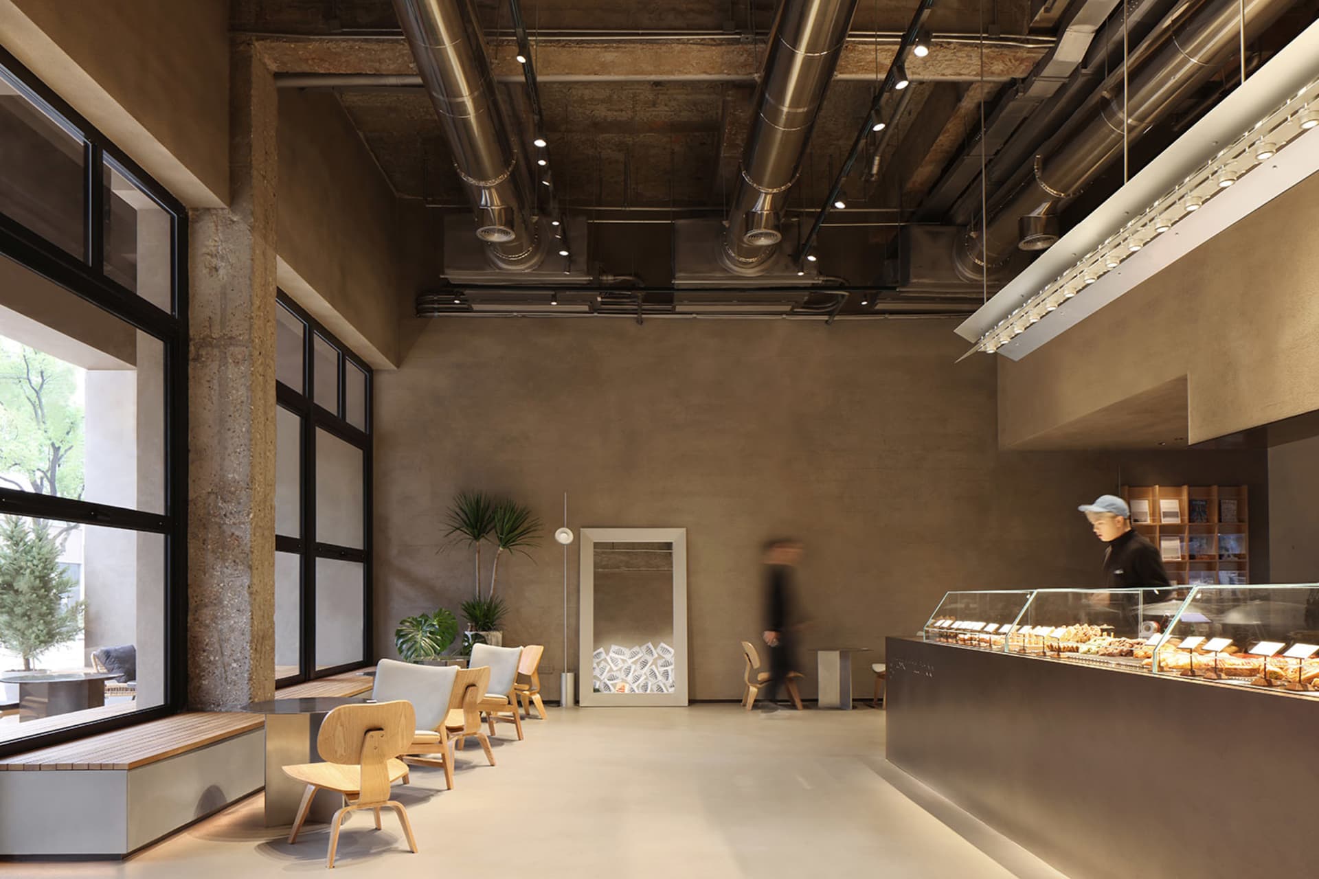 A modern restaurant with high ceilings, natural light, and comfortable seating areas with chairs and dining tables
