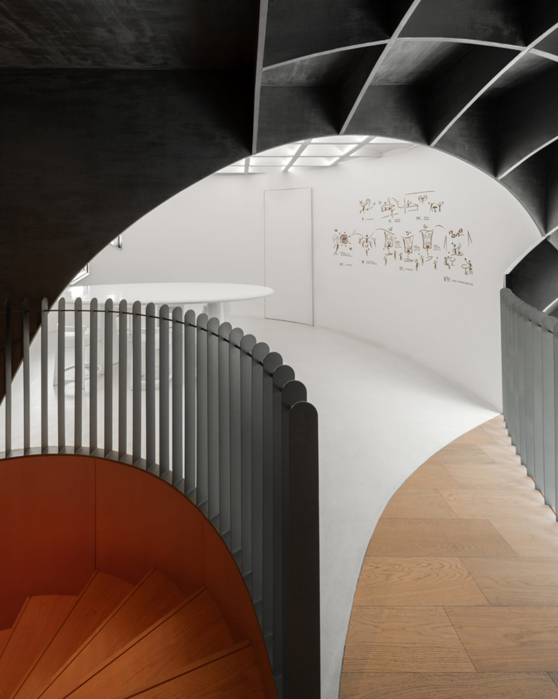 A spiral staircase with a wooden railing in a white-walled space