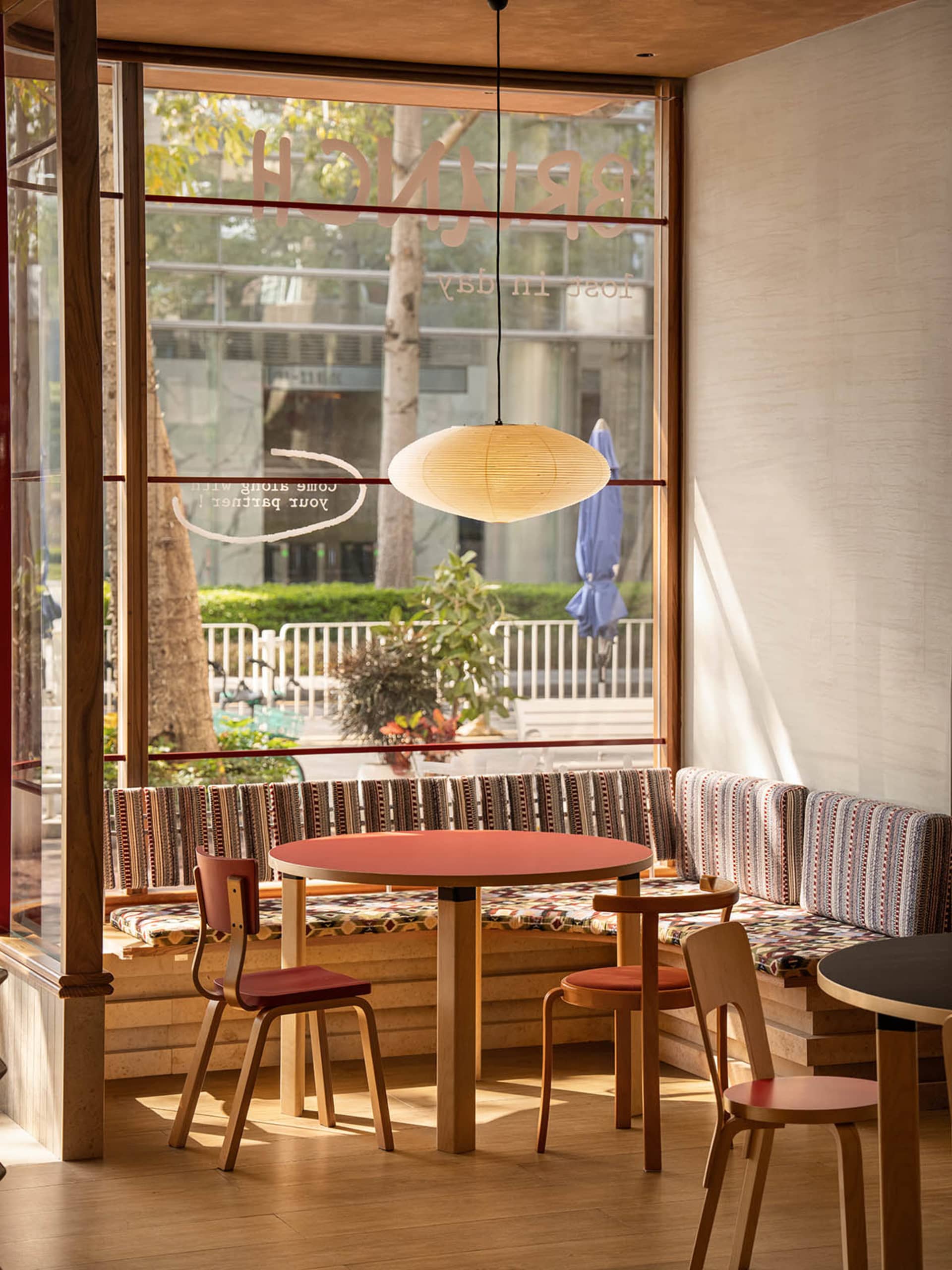 Modern dining space with wooden elements, red accents, and natural light from a large window