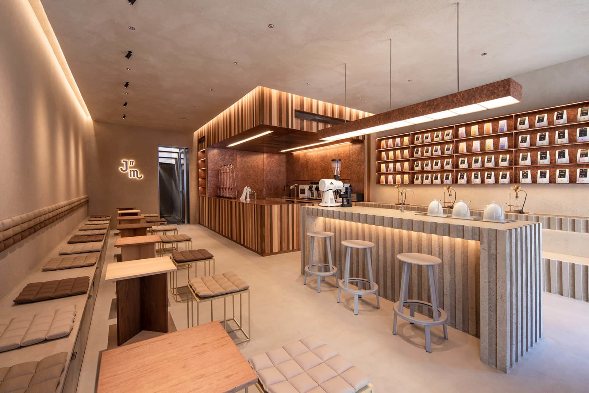 A cozy cafe with a bar area, stools, and dining tables, featuring comfortable seating and scattered cups and bottles