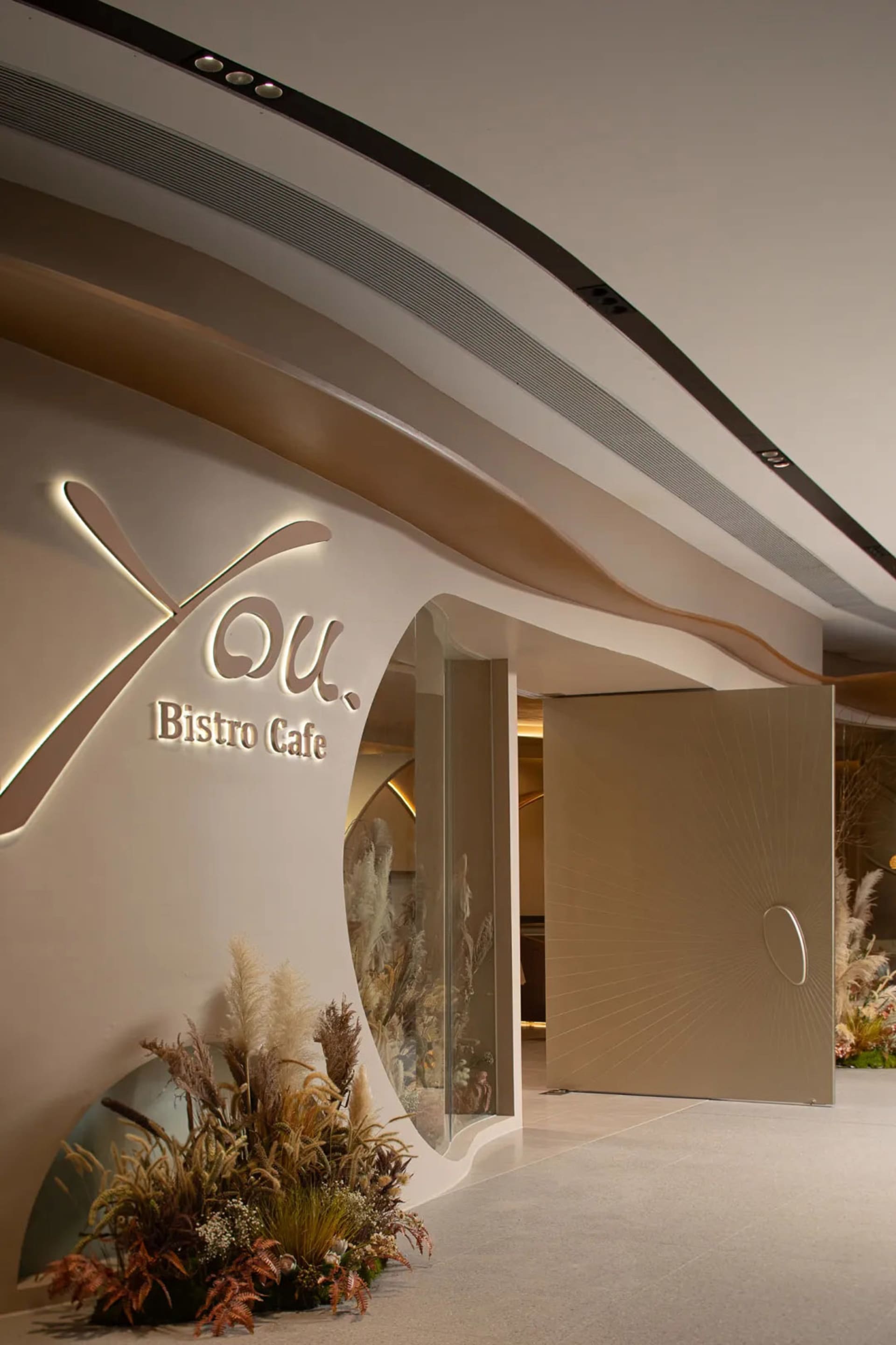 Spacious bistro cafe with brown and white walls, potted plants, and a modern atmosphere