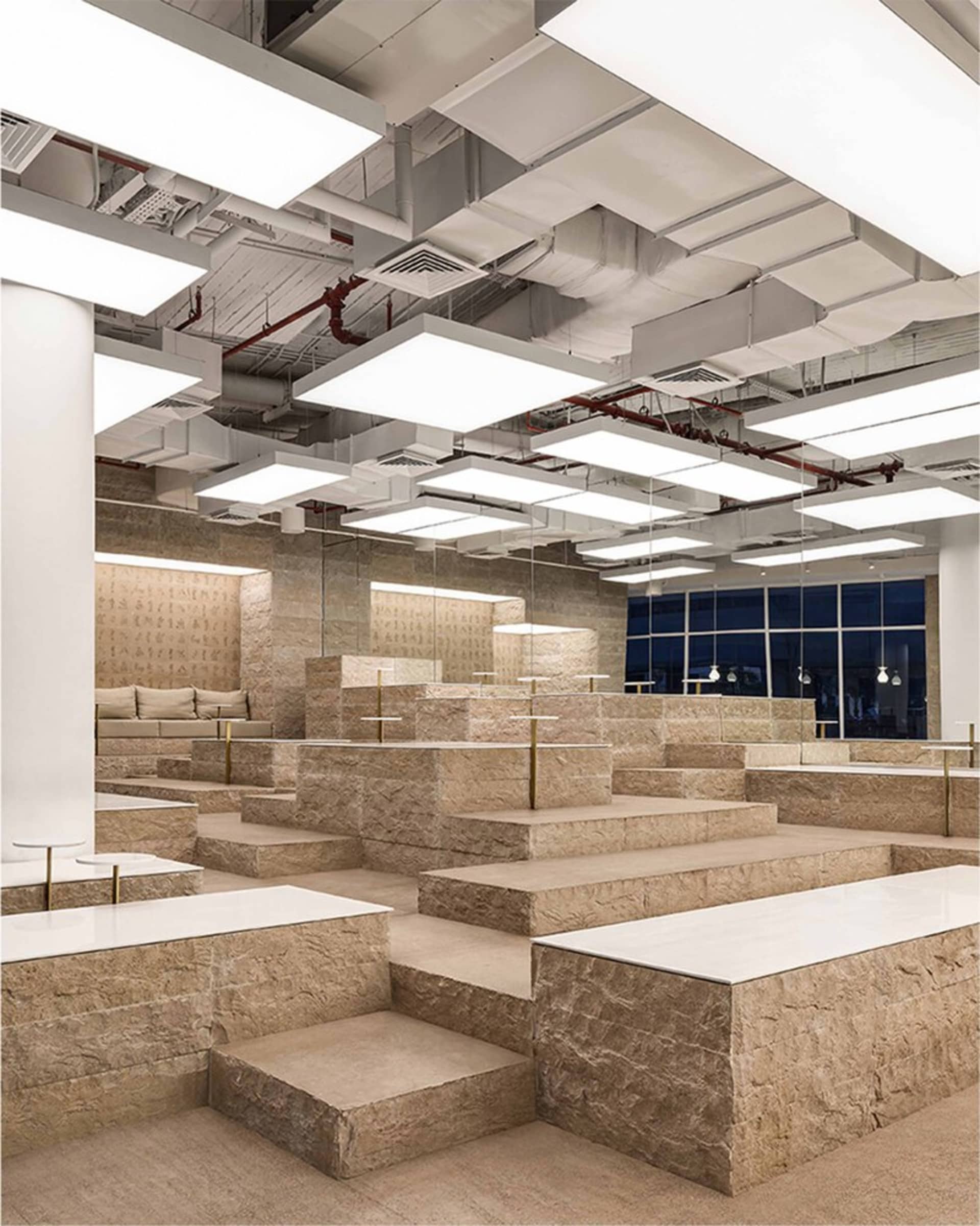 A spacious outdoor area with stone steps, benches, and stone tile flooring, featuring a dimly lit and cozy ambiance