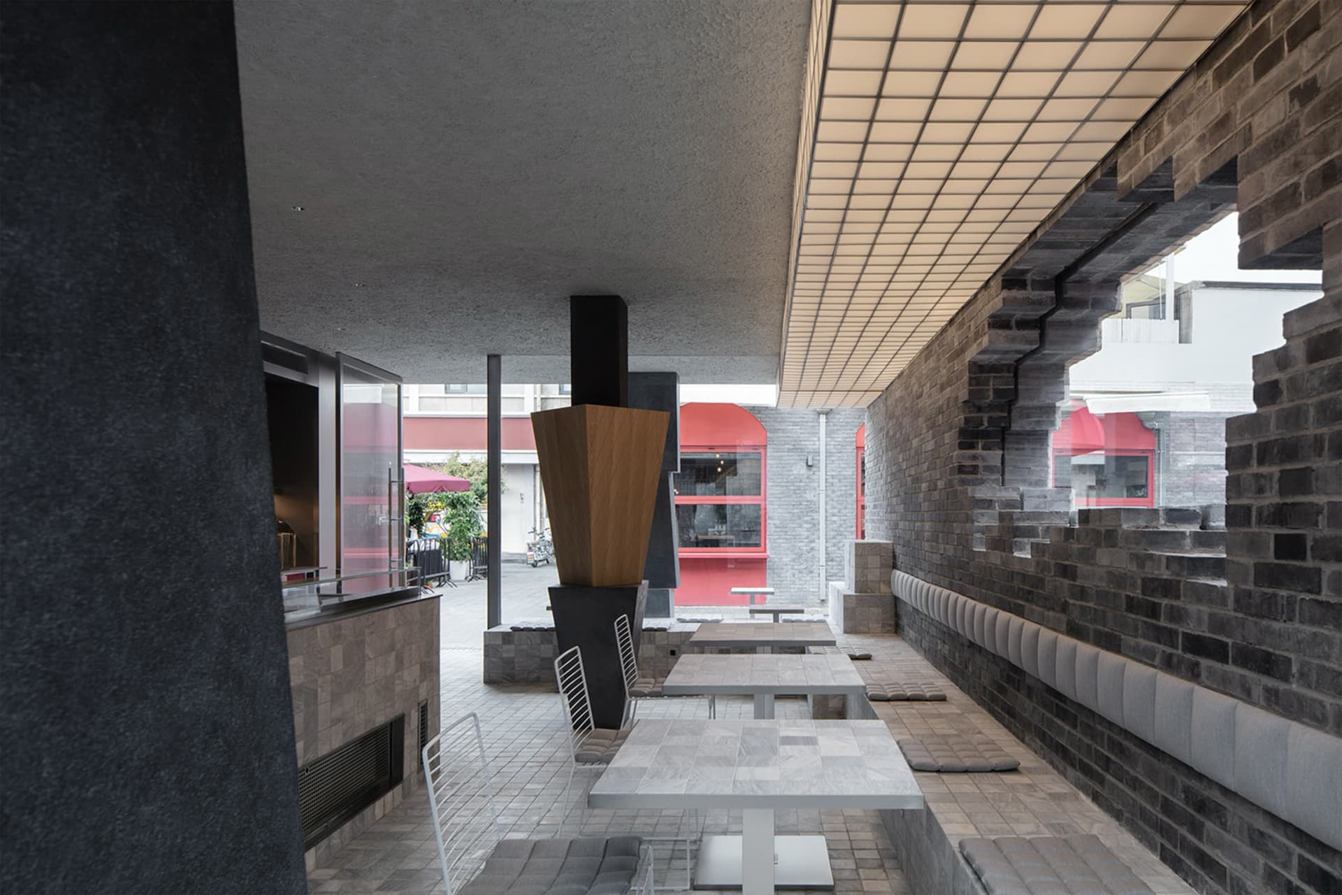 現代餐廳內部，包含用餐區、吧台與多種座位選擇，採用混凝土與木質材質，並配以溫暖頂燈照明