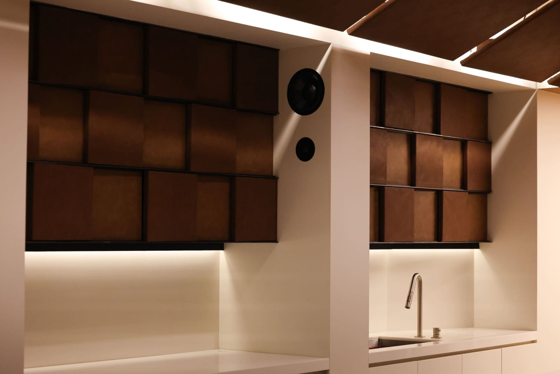 Kitchen with white cabinets, brown wooden walls, and a marble countertop, giving off a clean and modern vibe