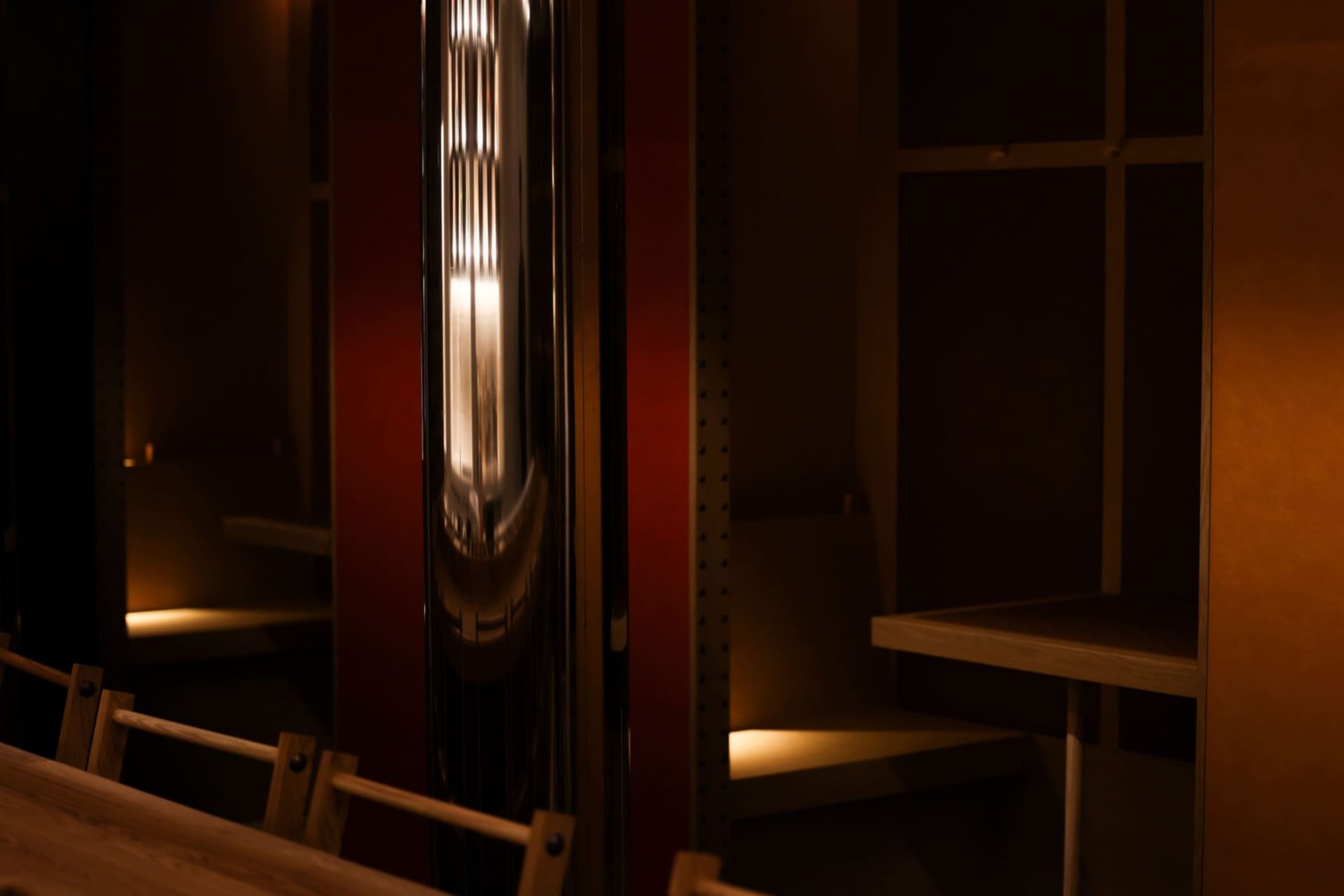 Cozy coffee shop interior with a red accent wall, metal doorway, wooden benches, and a dining table