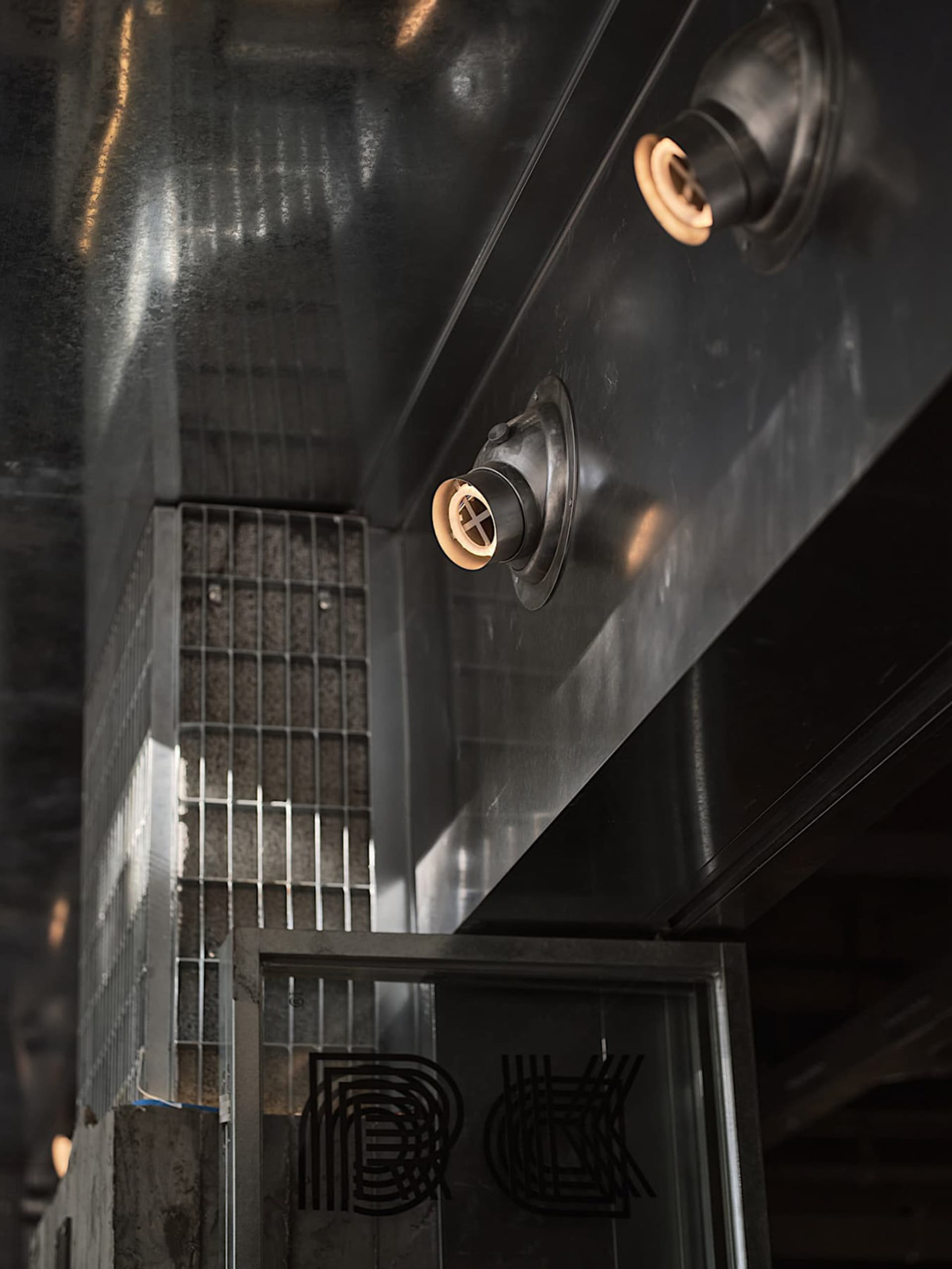 Industrial building with a metal door and window, lit by two overhead lights, suggesting a functional storage or work area