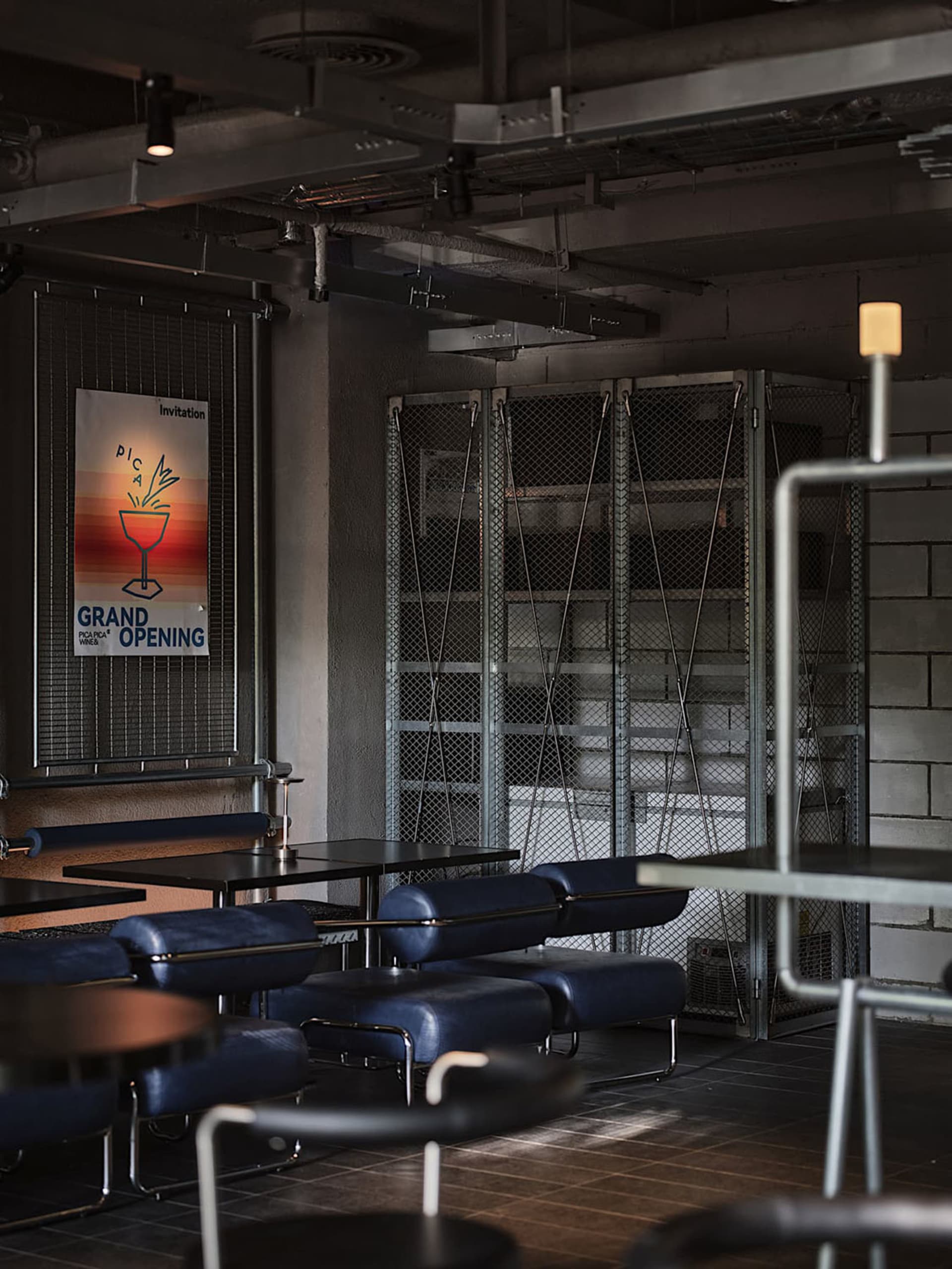 Cozy cafe with brick and metal walls, multiple tables, chairs, and a couch, creating a warm and inviting atmosphere