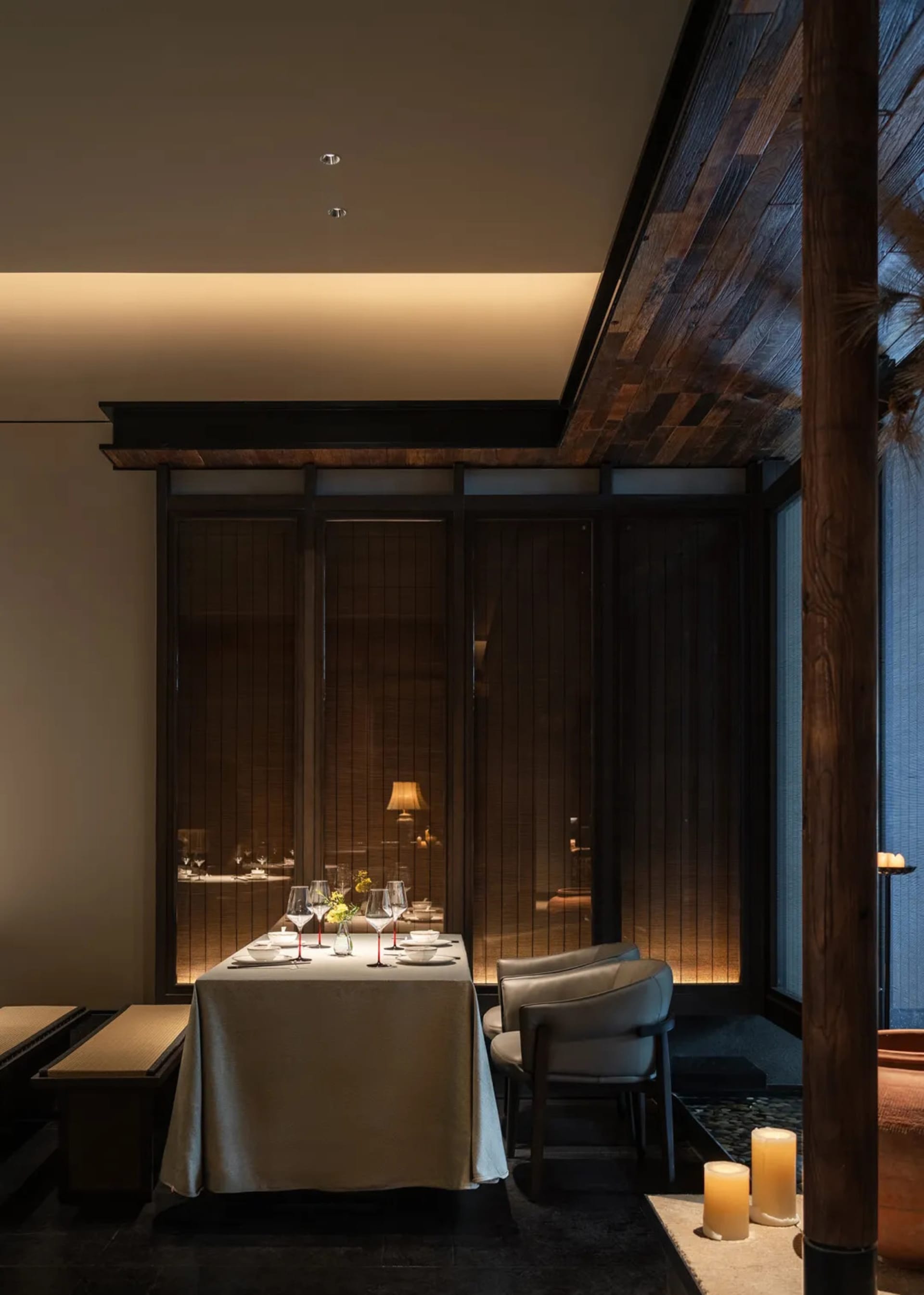 A sophisticated dining area with a table set for a meal, featuring fine dinnerware, wine glasses, and decorative items