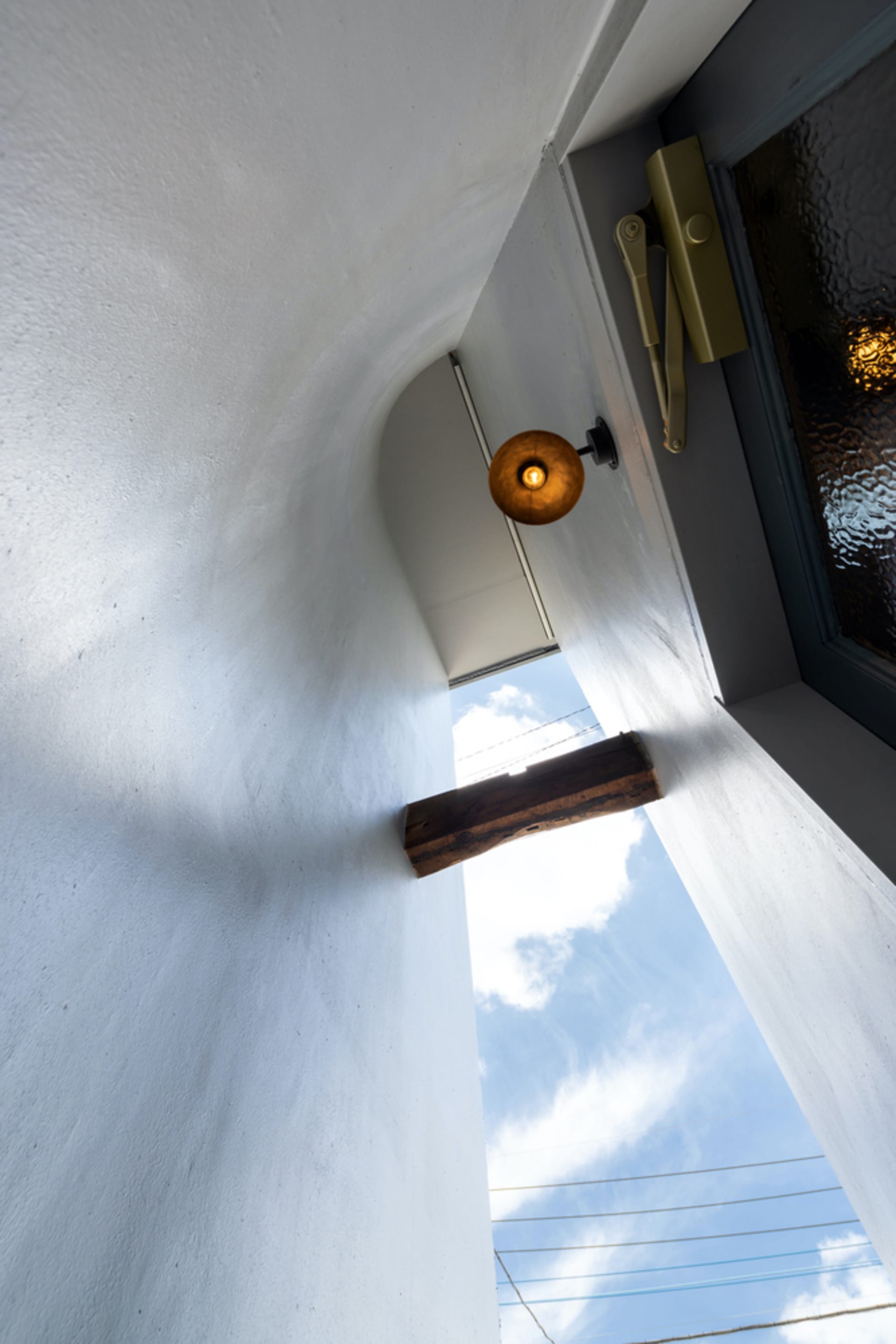 Open restaurant space with a white wall, a doorway, and two hanging lights providing illumination