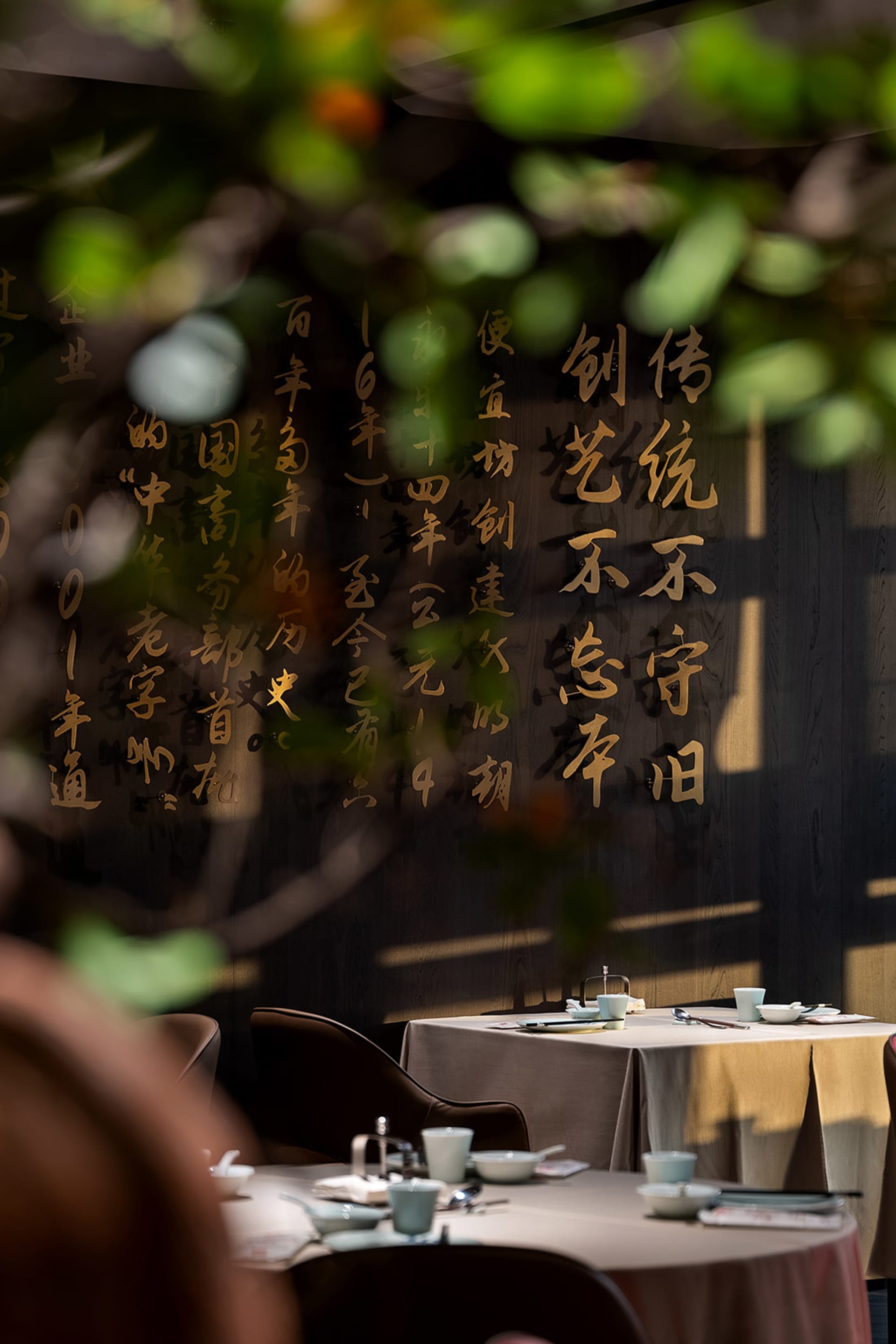 一組餐桌椅，牆上飾有中文書法，周圍擺放杯具，散發溫暖親切的氛圍