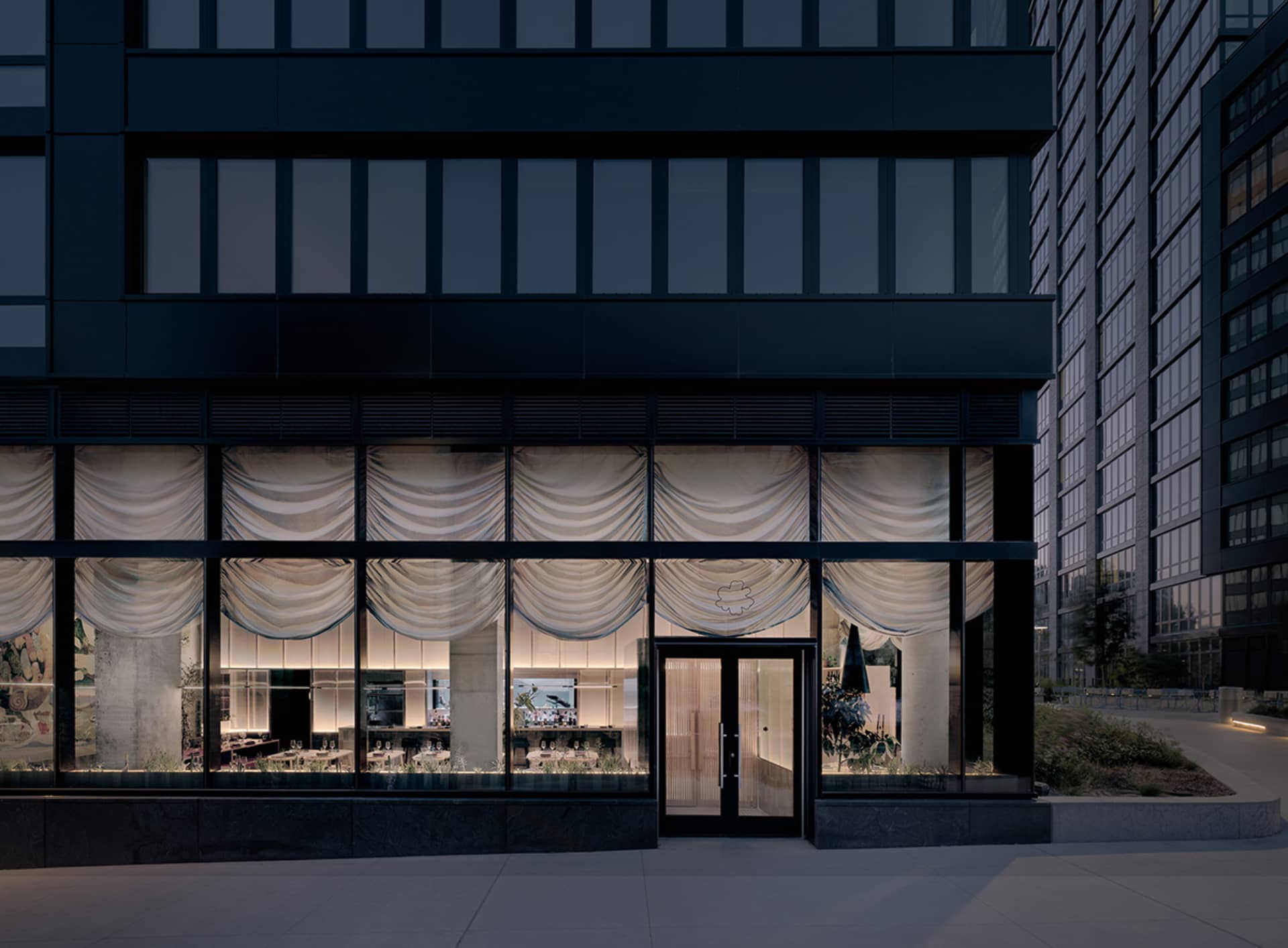 Elegant dining space with a black building facade, a large window, and a beautifully decorated interior with a dining table and chairs