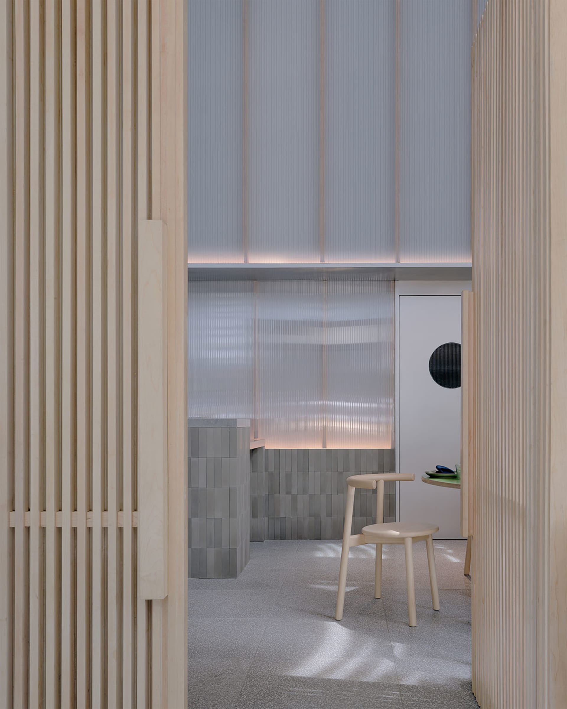 Cozy small room with wooden walls and floors, featuring a dining table, couch, and two chairs, with a warm and inviting atmosphere
