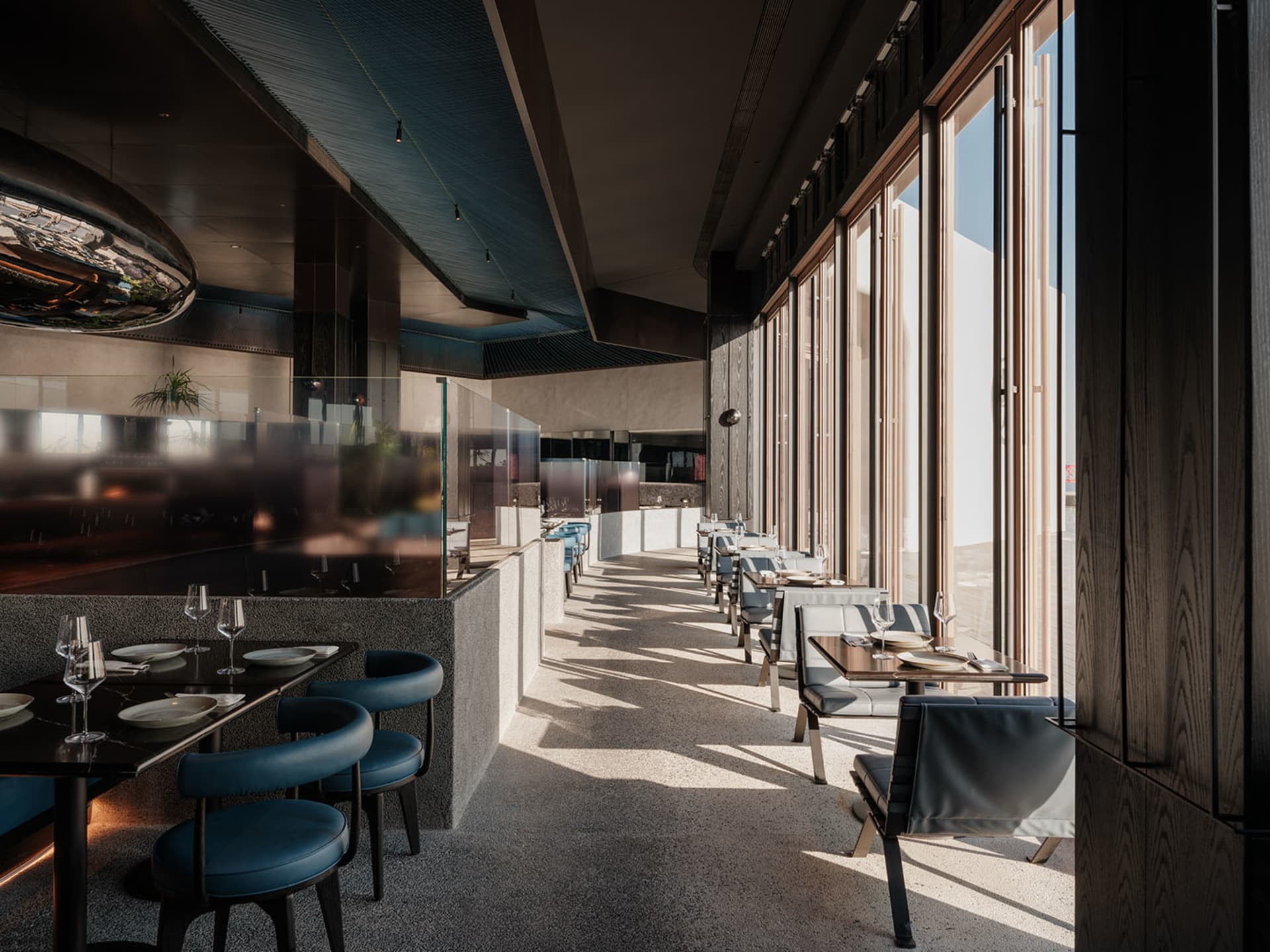 Calm and inviting restaurant with chairs, tables, and wine glasses, set against a backdrop of natural light and large windows