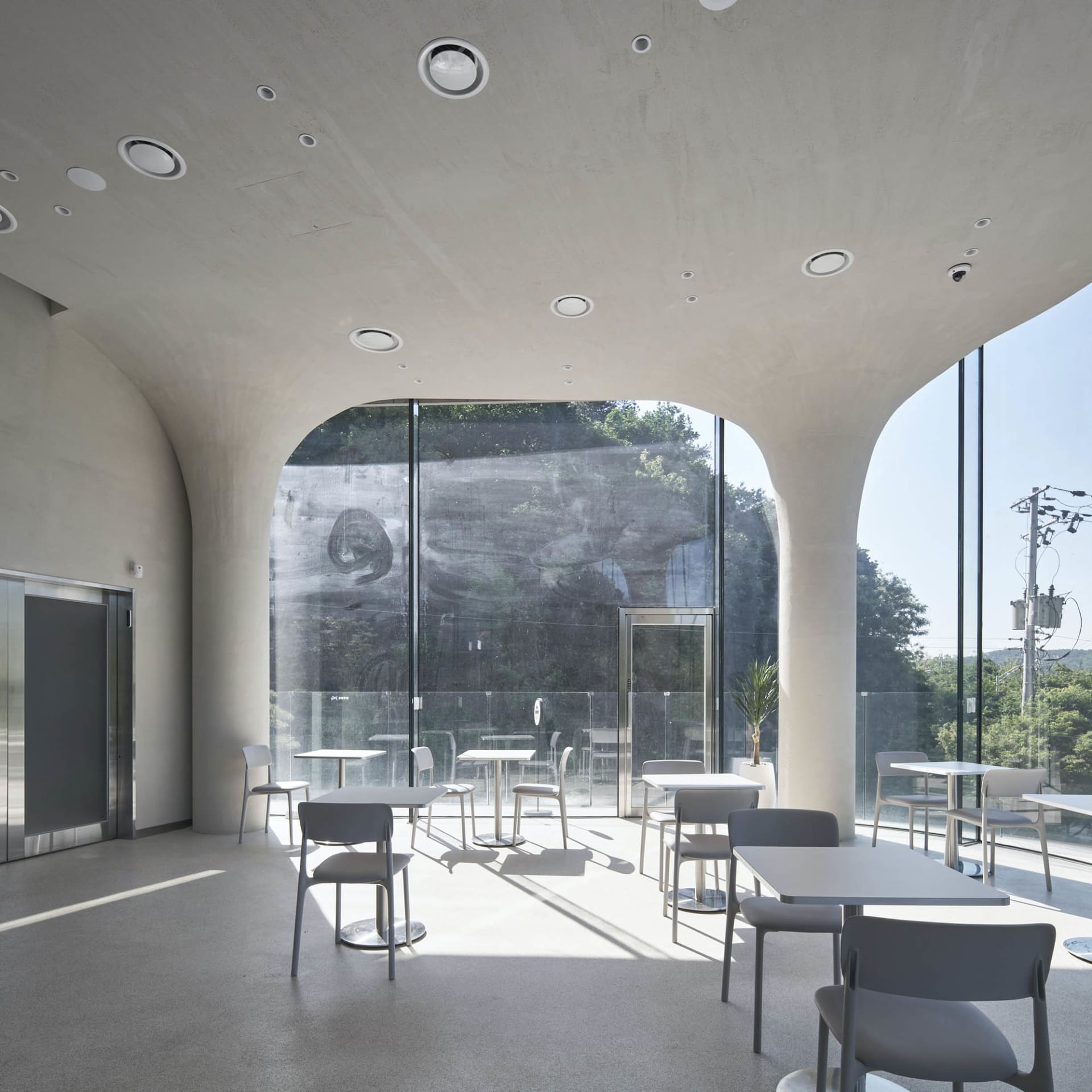 A modern restaurant interior with multiple dining tables and chairs, well-lit for a comfortable atmosphere