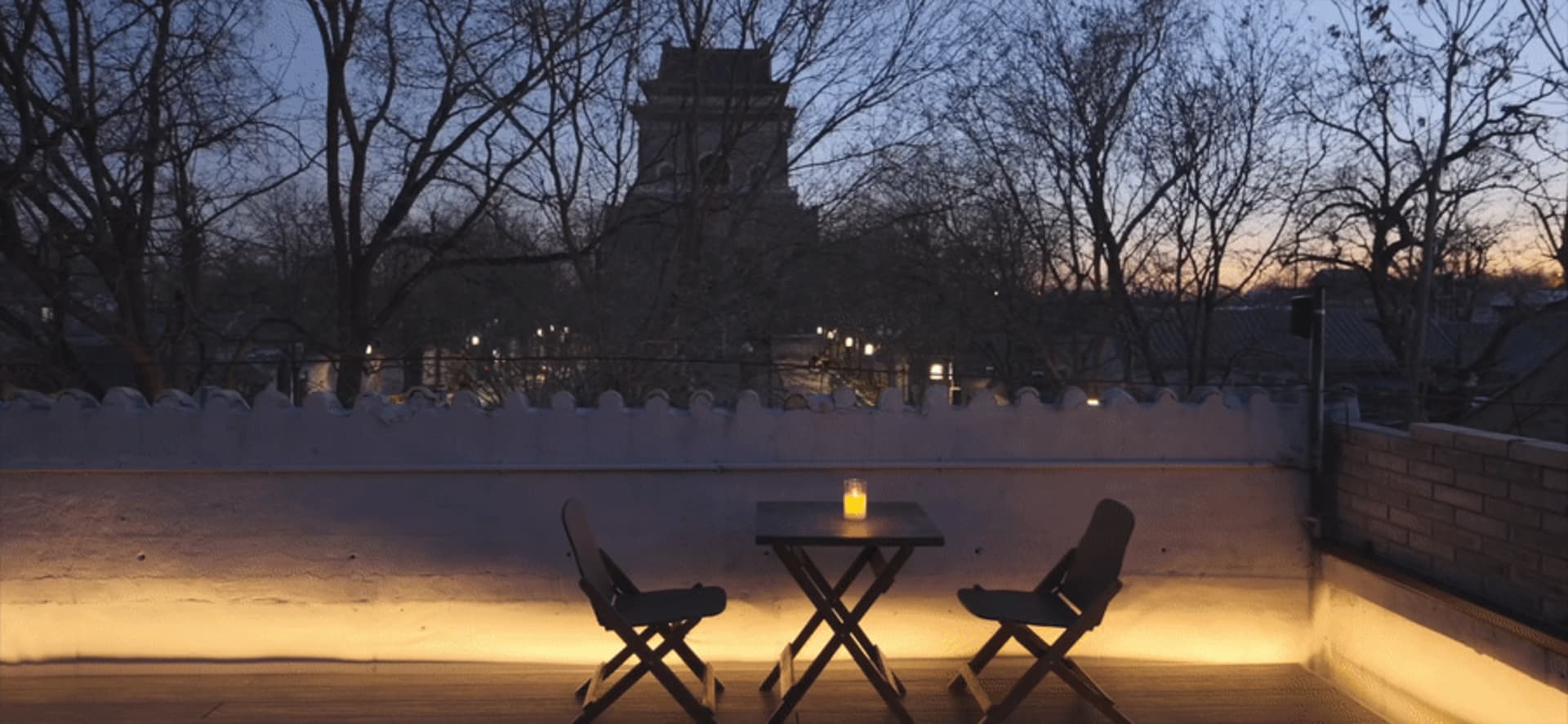 A modern dining space with two chairs and a small table, featuring a candle and clean lines, well-lit by natural or artificial light