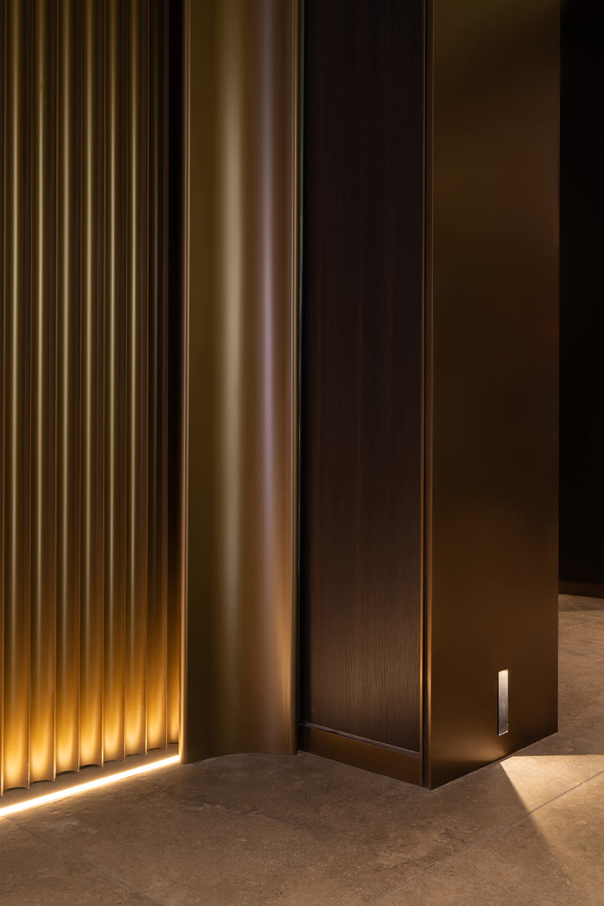 A dark hallway with two large wooden doors featuring gold accents, creating a sense of luxury and sophistication