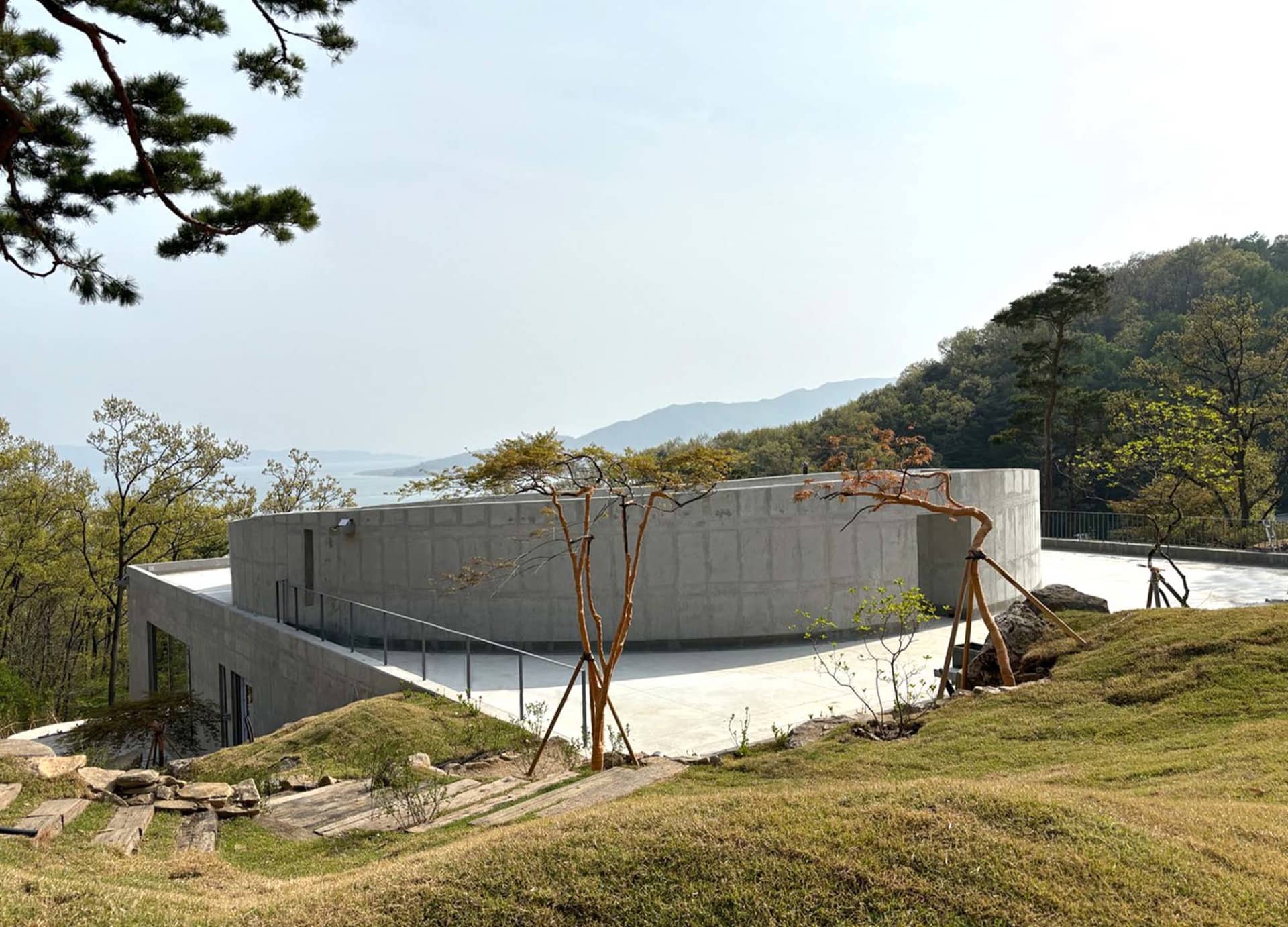 寧靜開闊空間中，混凝土房屋被樹木環繞，氛圍平靜
