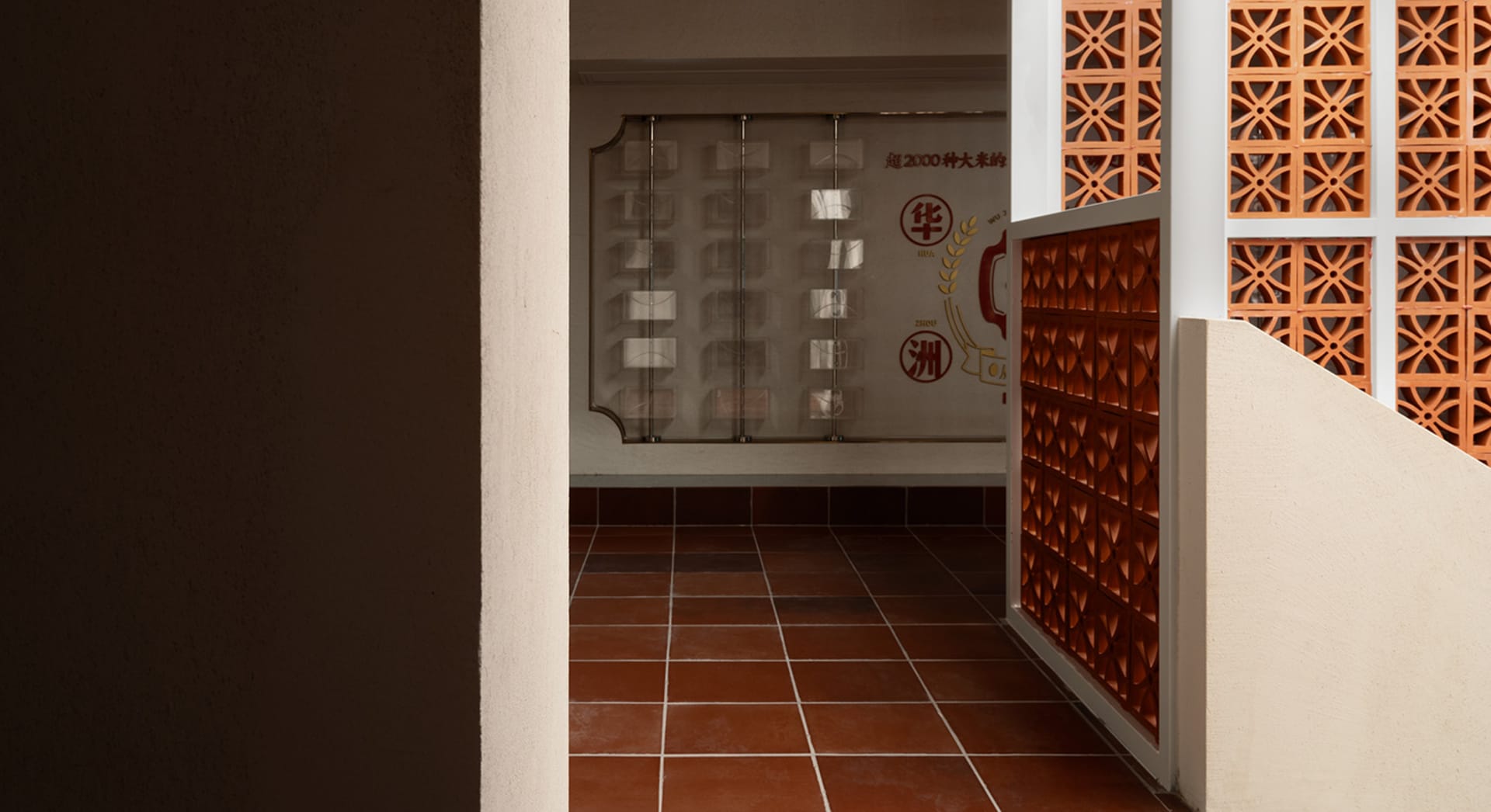 Dimly lit hallway with a red brick wall, a white wall, and a tile floor, featuring two doors
