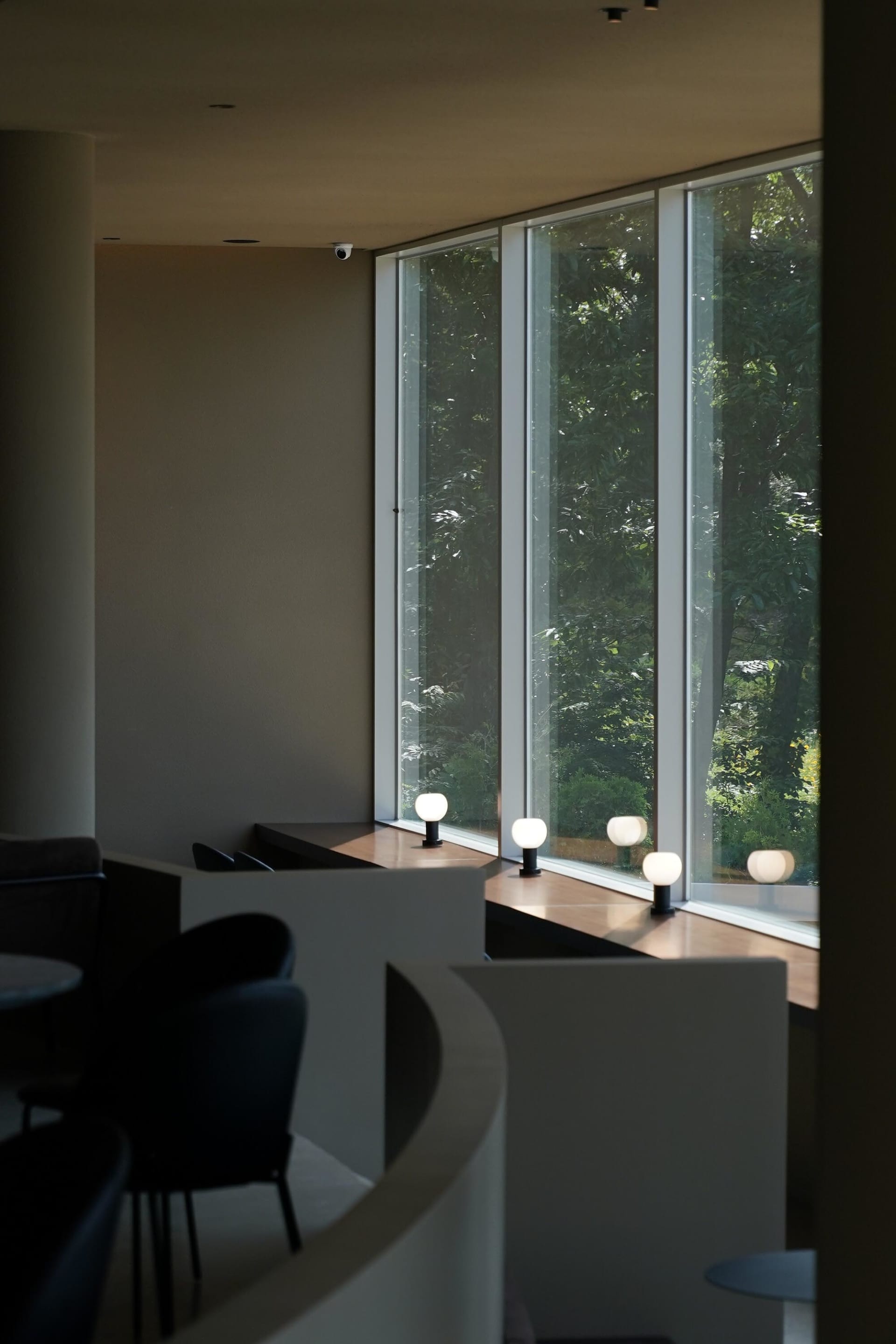Bright dining room with large windows, two chairs, and three dining tables, with a warm and inviting atmosphere