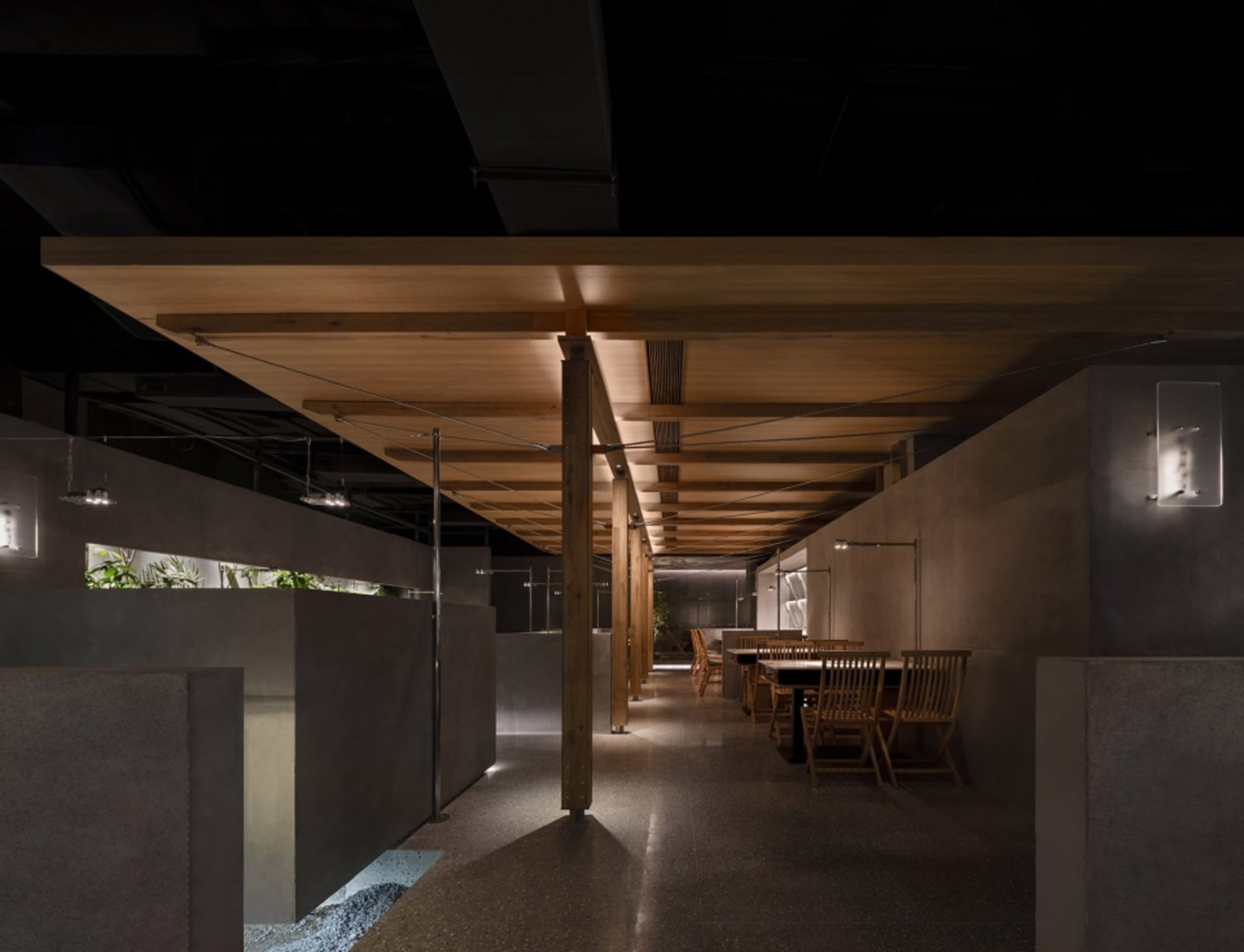 Modern restaurant interior with wooden floors, tables, chairs, and potted plants, creating a welcoming atmosphere