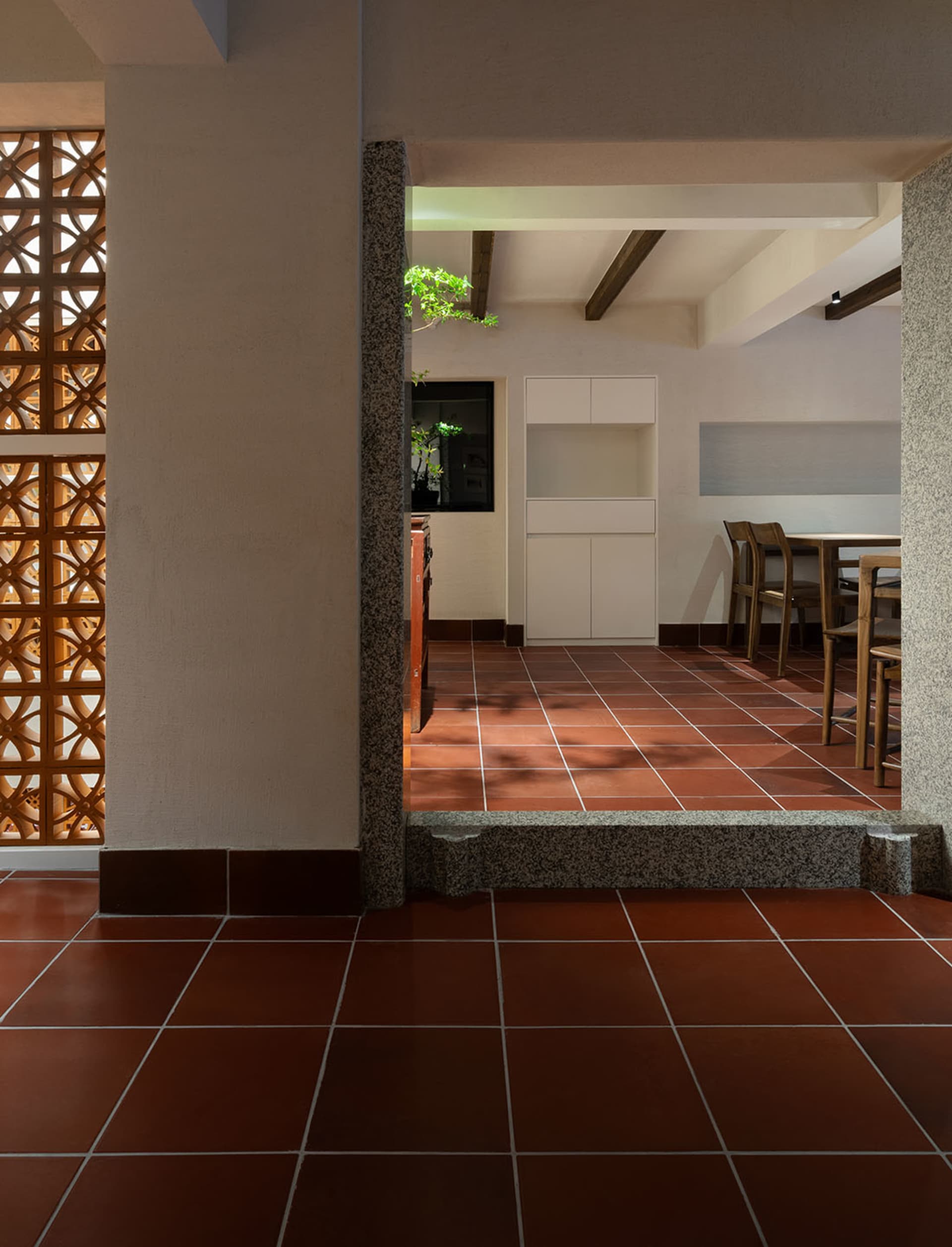 Warm and inviting kitchen space with red tile flooring, a dining table, chairs, and a potted plant