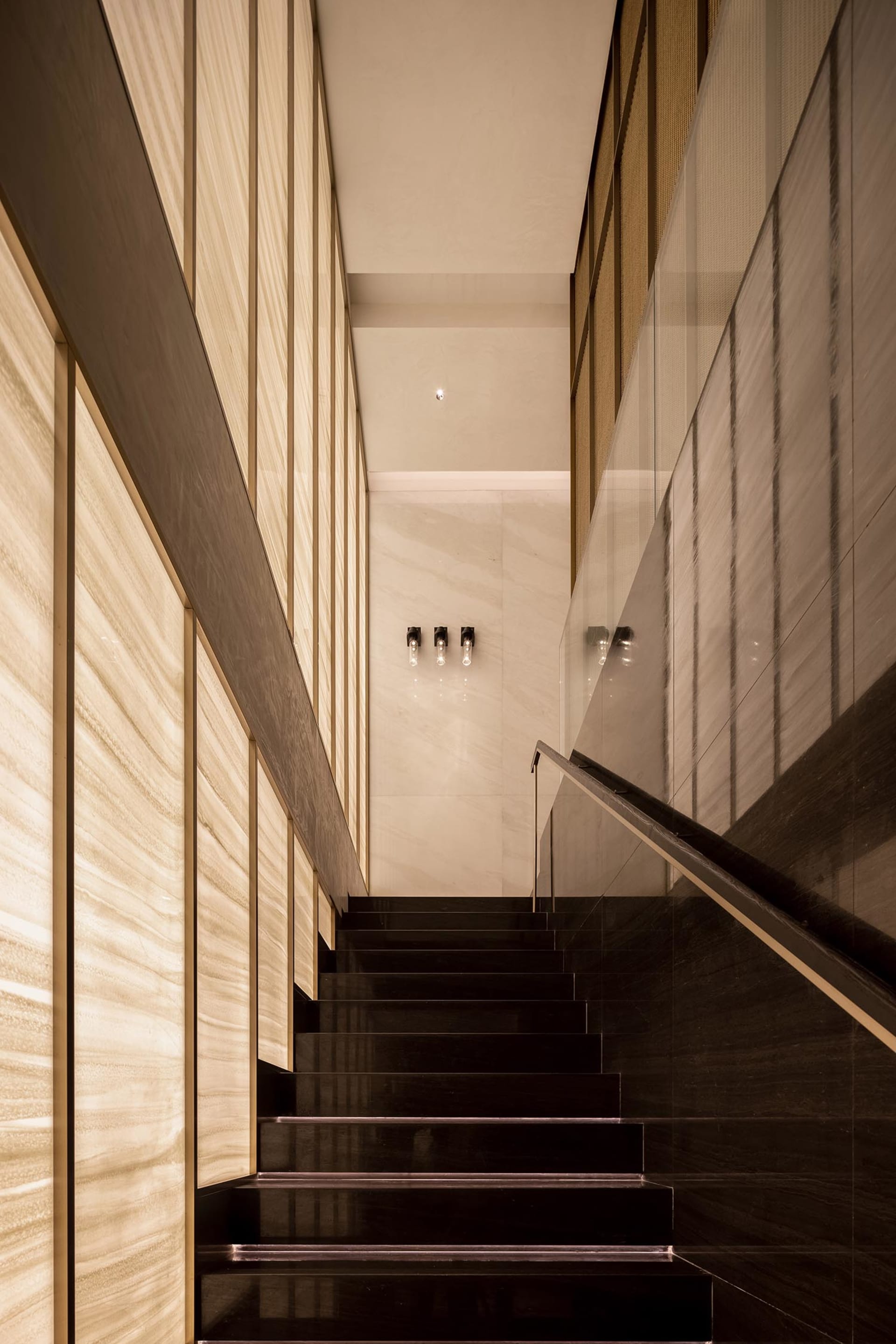 A well-lit stairwell with wooden stairs and black railings, possibly in a hotel or office building
