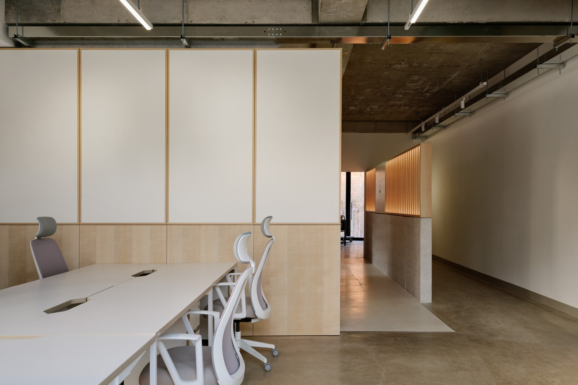 A clean and organized office space with a large white table surrounded by several chairs, giving a professional work environment