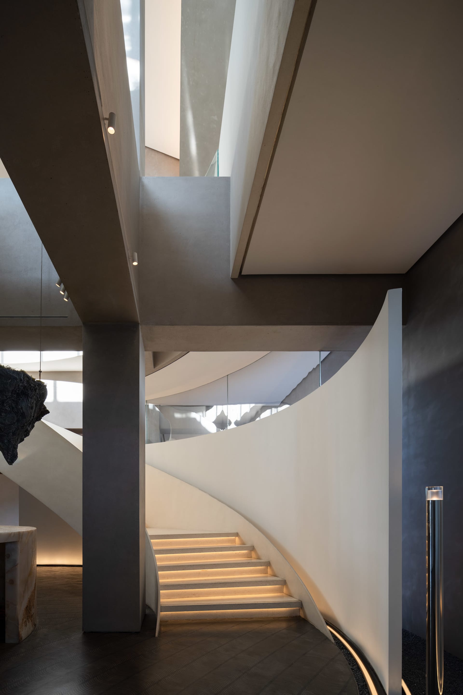 A spiral staircase in a museum setting with sculptures on display, made of wood with a sense of history and artistic expression