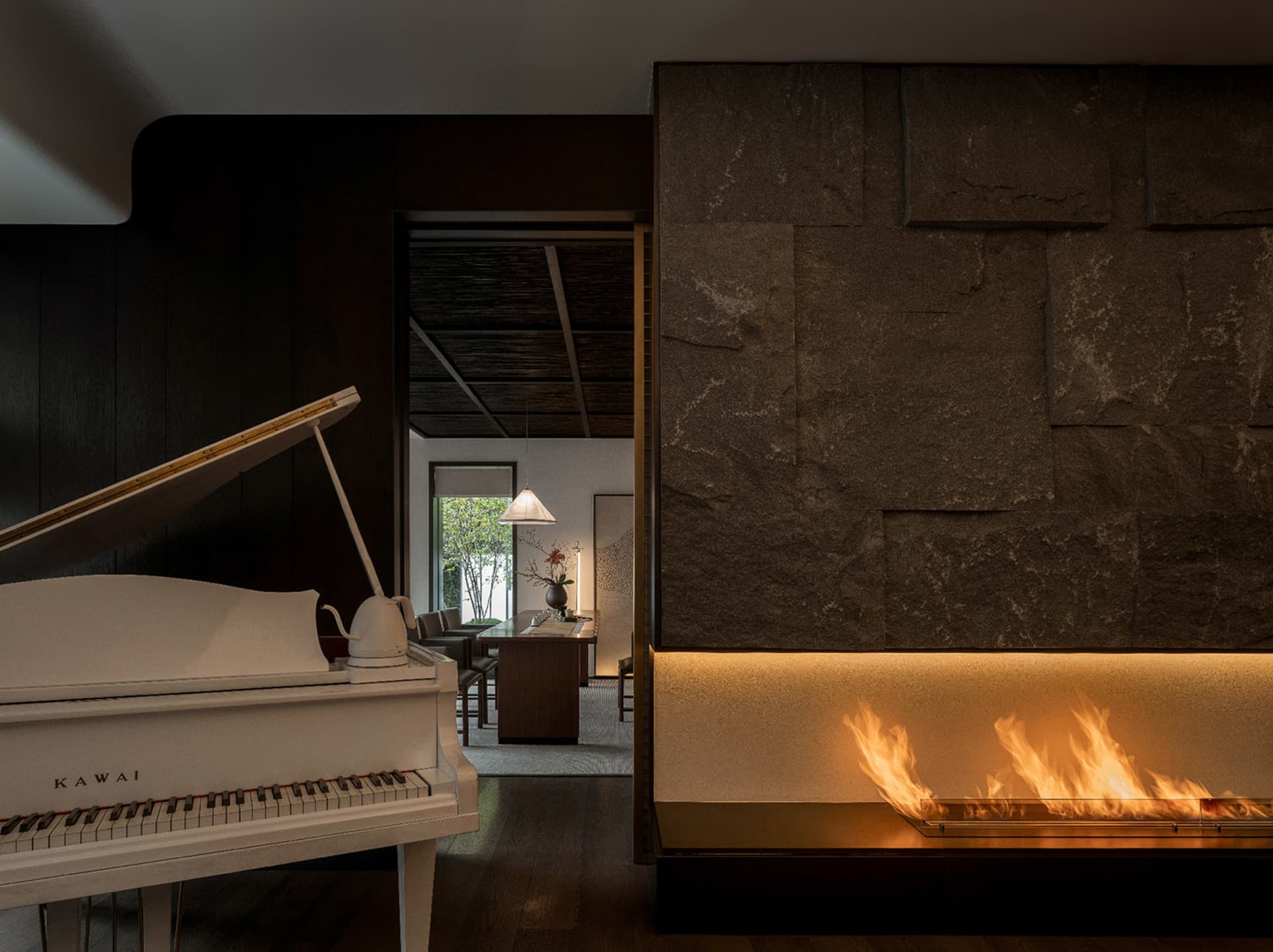 Cozy living room with a white piano, fireplace, couch, chairs, and decorative vase, creating a comfortable and inviting atmosphere