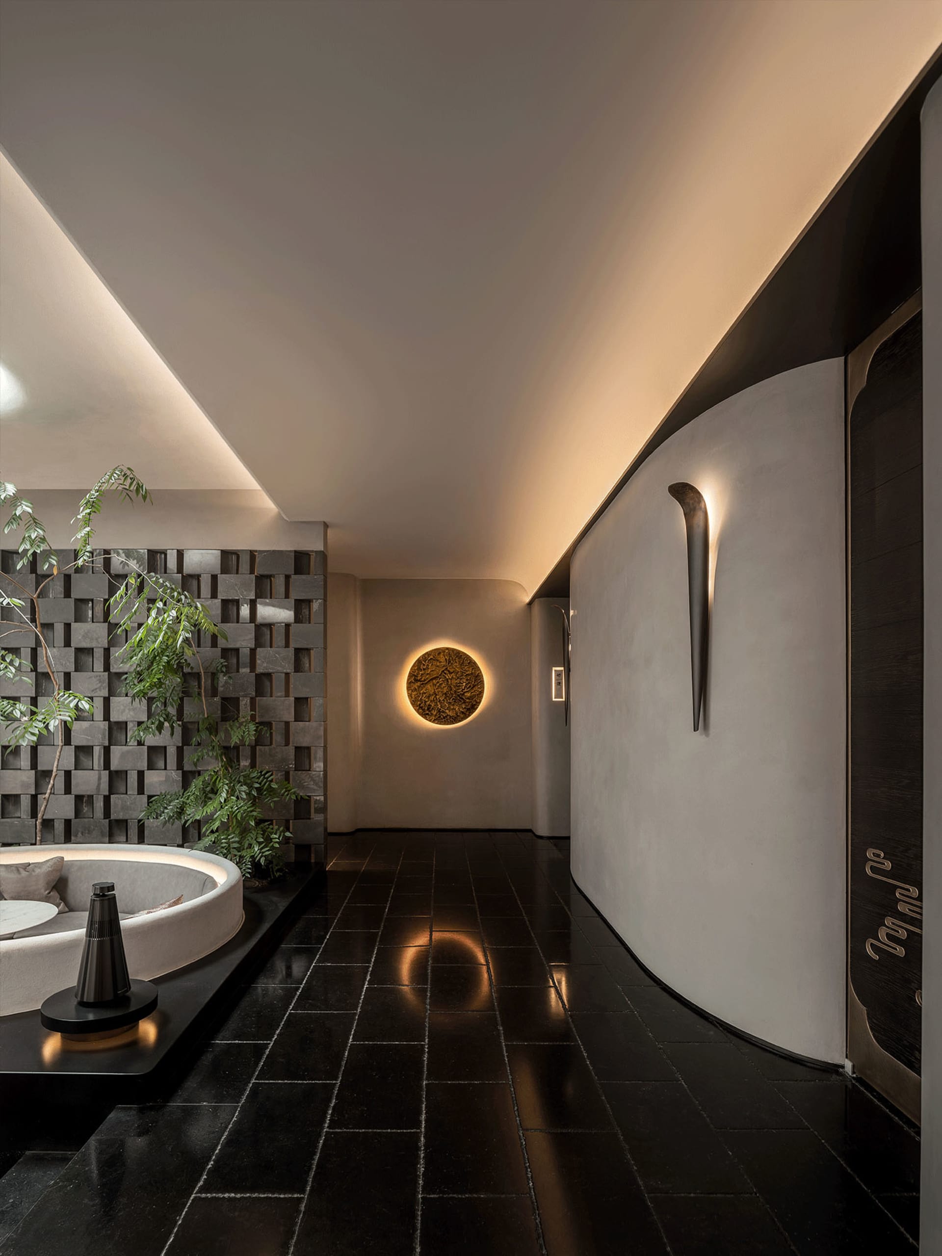 Cozy modern living area with a circular table, chairs, potted plants, and black tile flooring