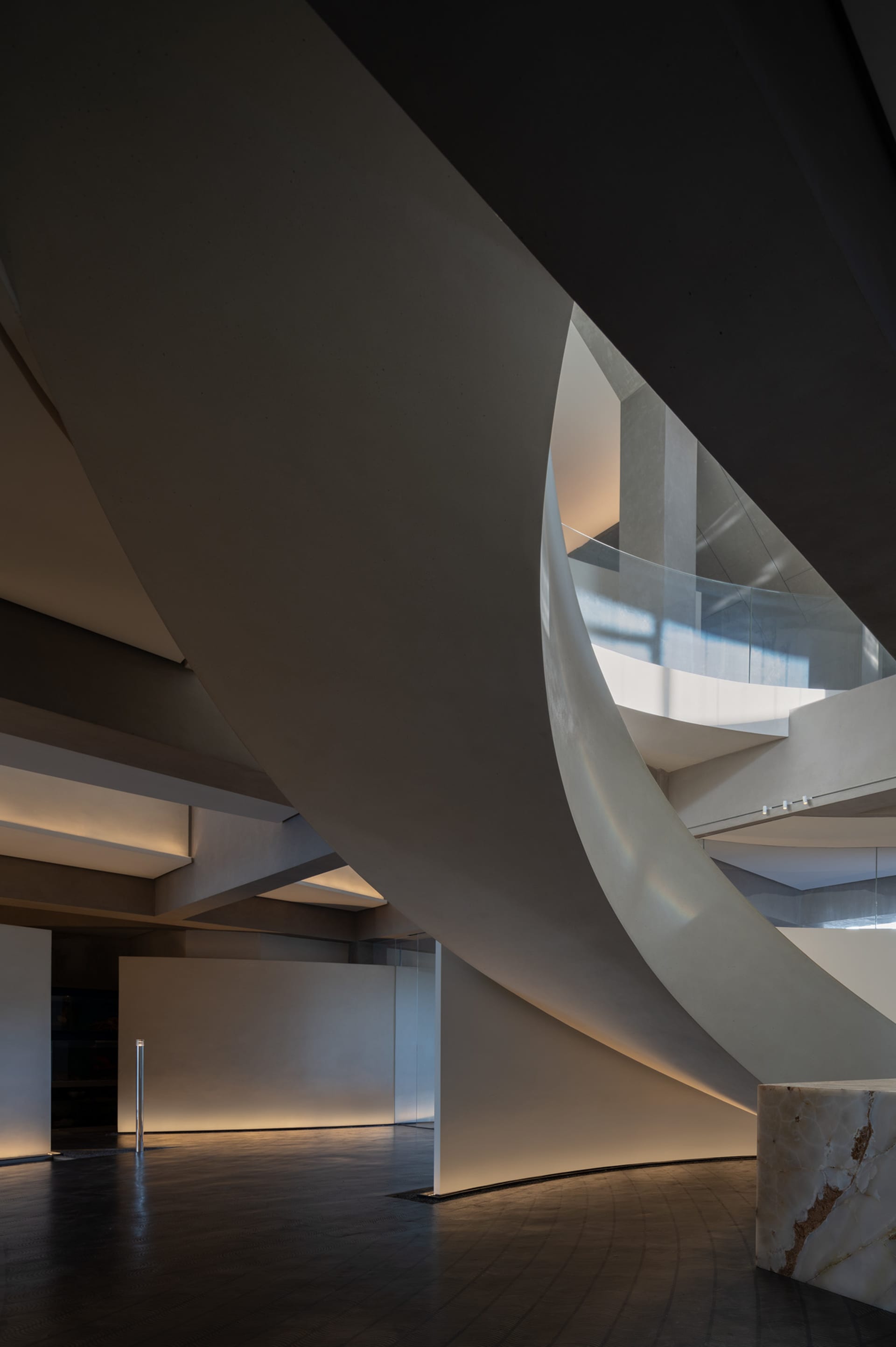 A spiral staircase with a white color scheme is surrounded by a glass enclosure in a rendered architectural scene