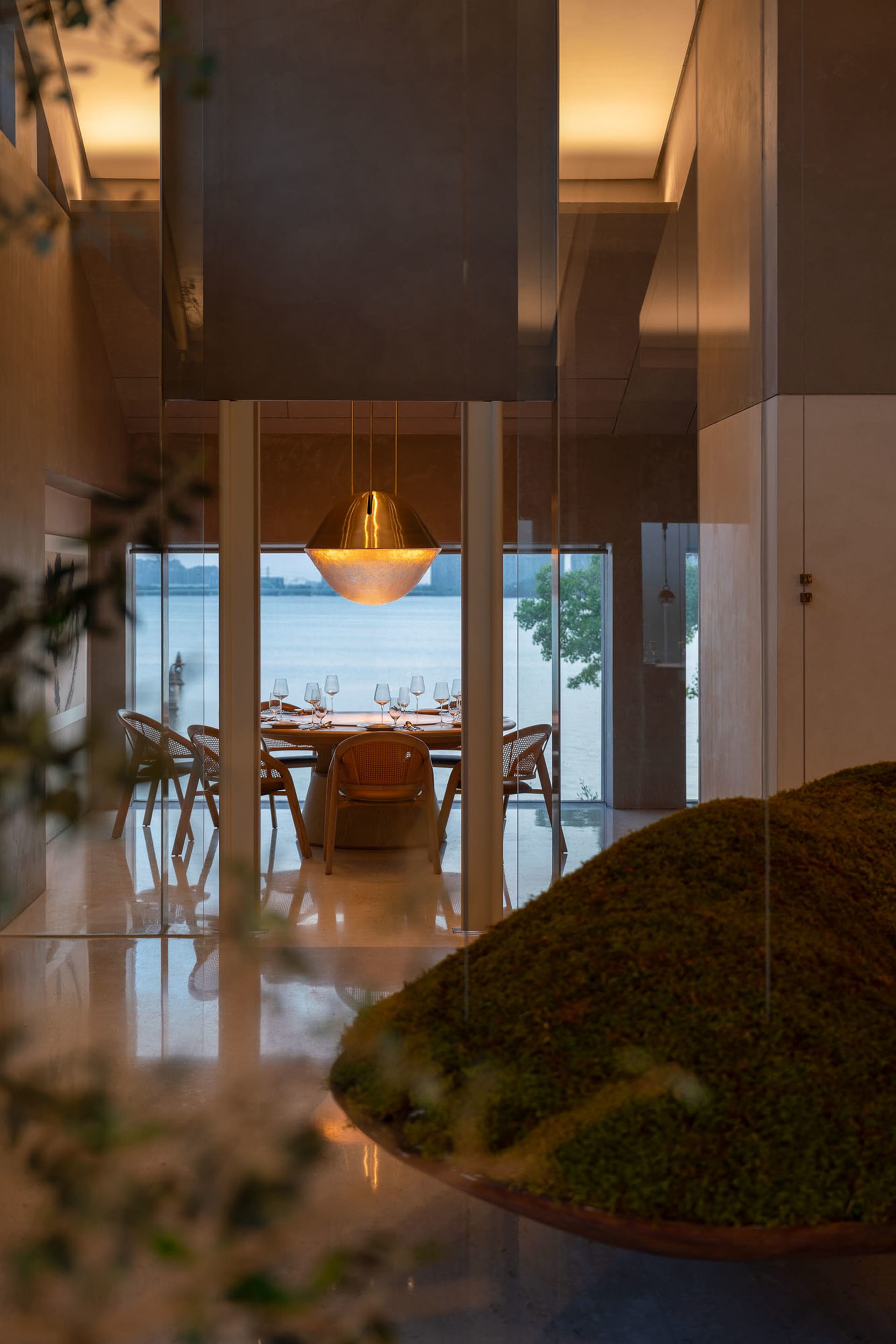 Bright and inviting open concept dining room with a wooden dining table, chairs, and a couch, featuring a potted plant and wine glasses