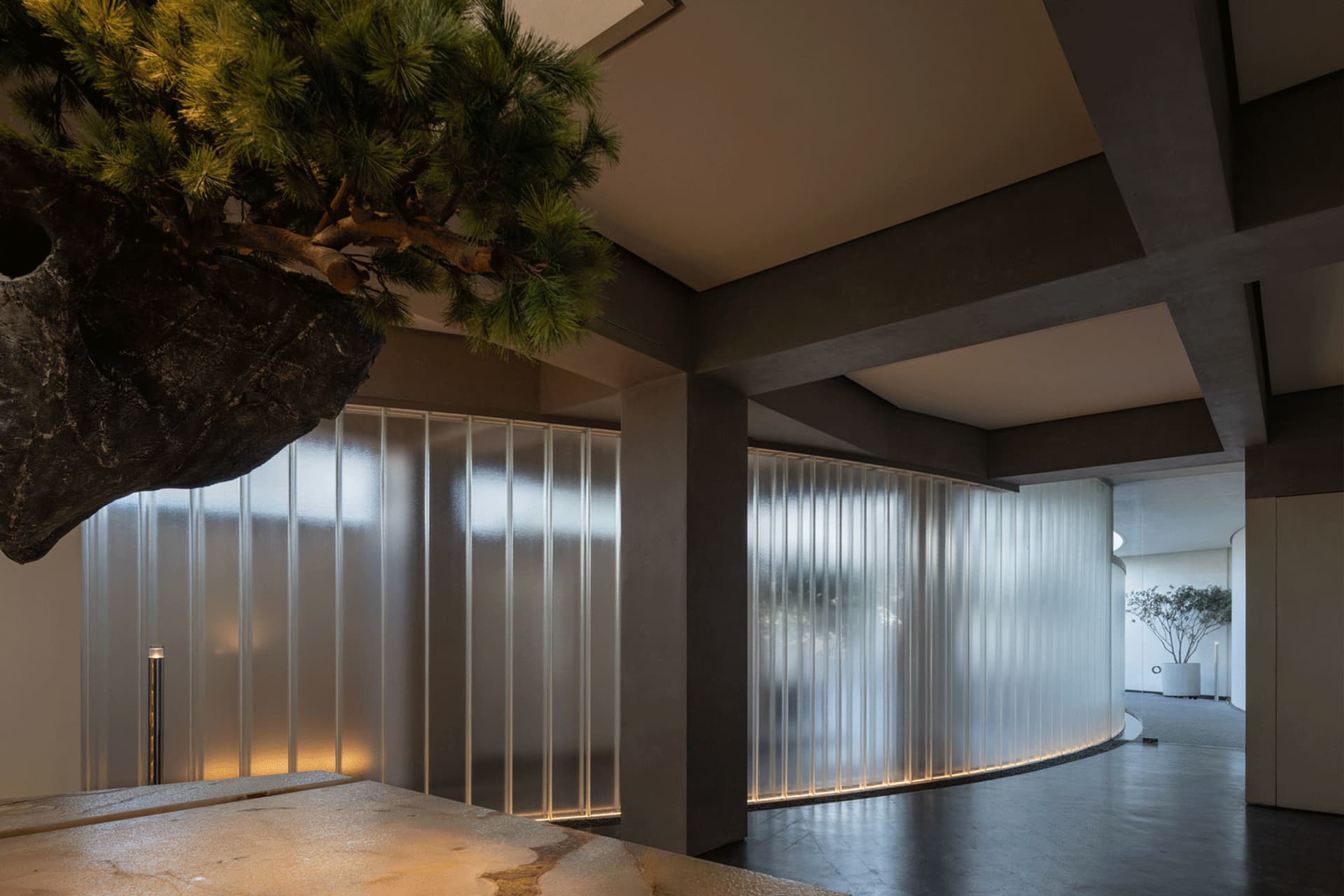 A modern room with a concrete wall, a rock wall, and potted plant, featuring two windows and a modern industrial aesthetic