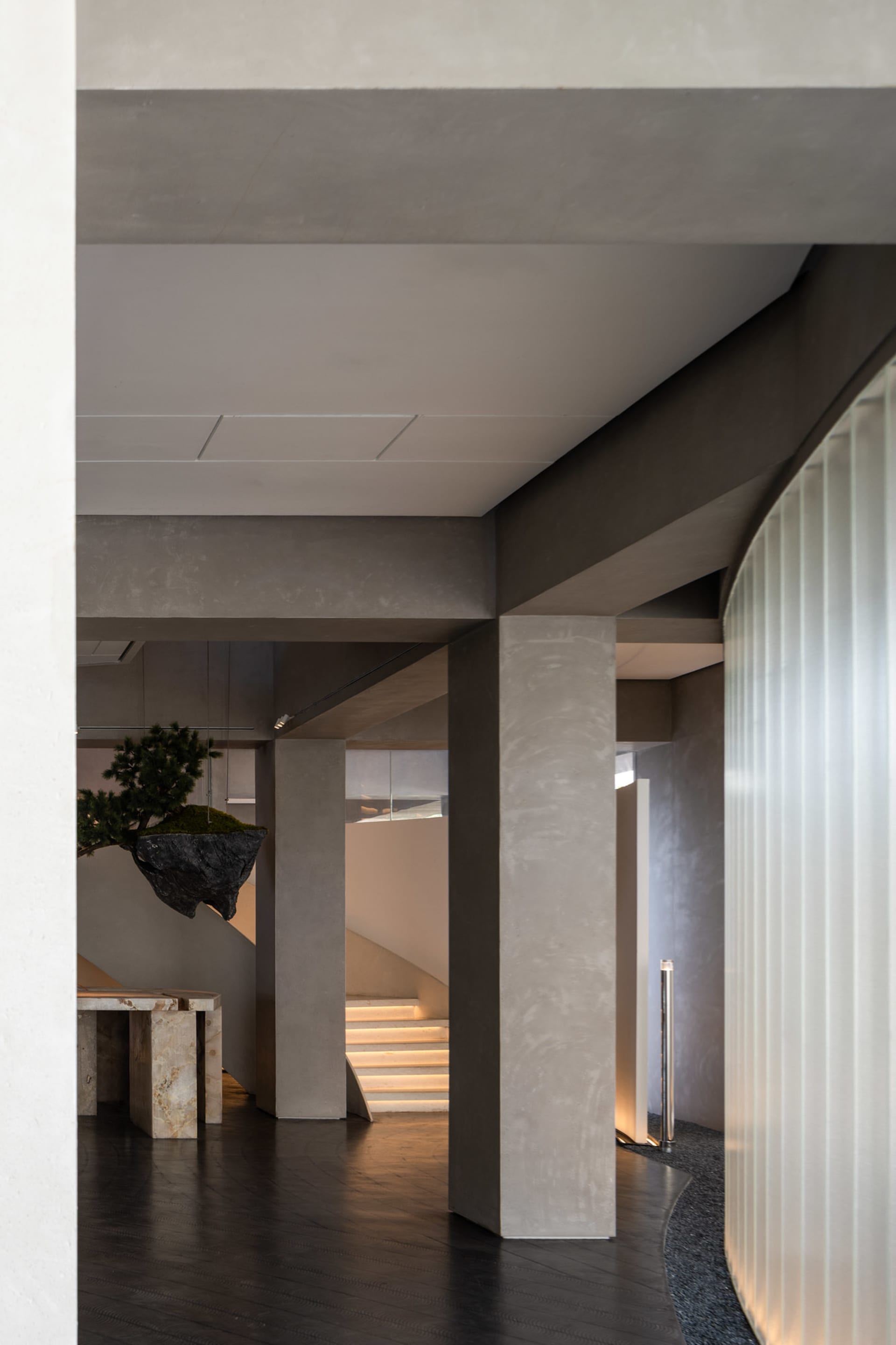 A modern interior space with multiple levels, concrete walls and floors, and potted plants, featuring a contemporary and stylish atmosphere
