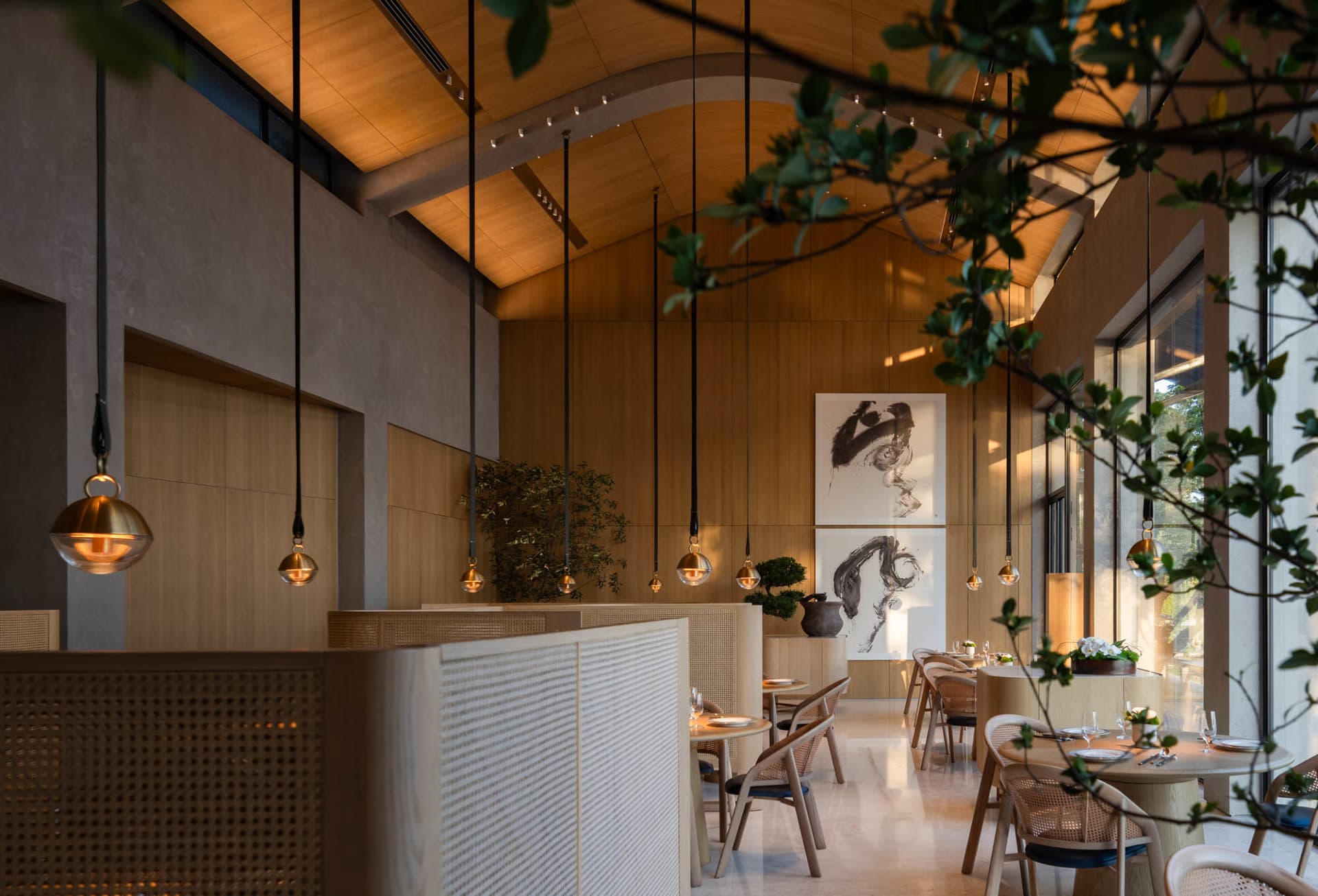 A modern restaurant interior with wooden walls and floors, featuring dining tables and chairs, well-lit and warm atmosphere