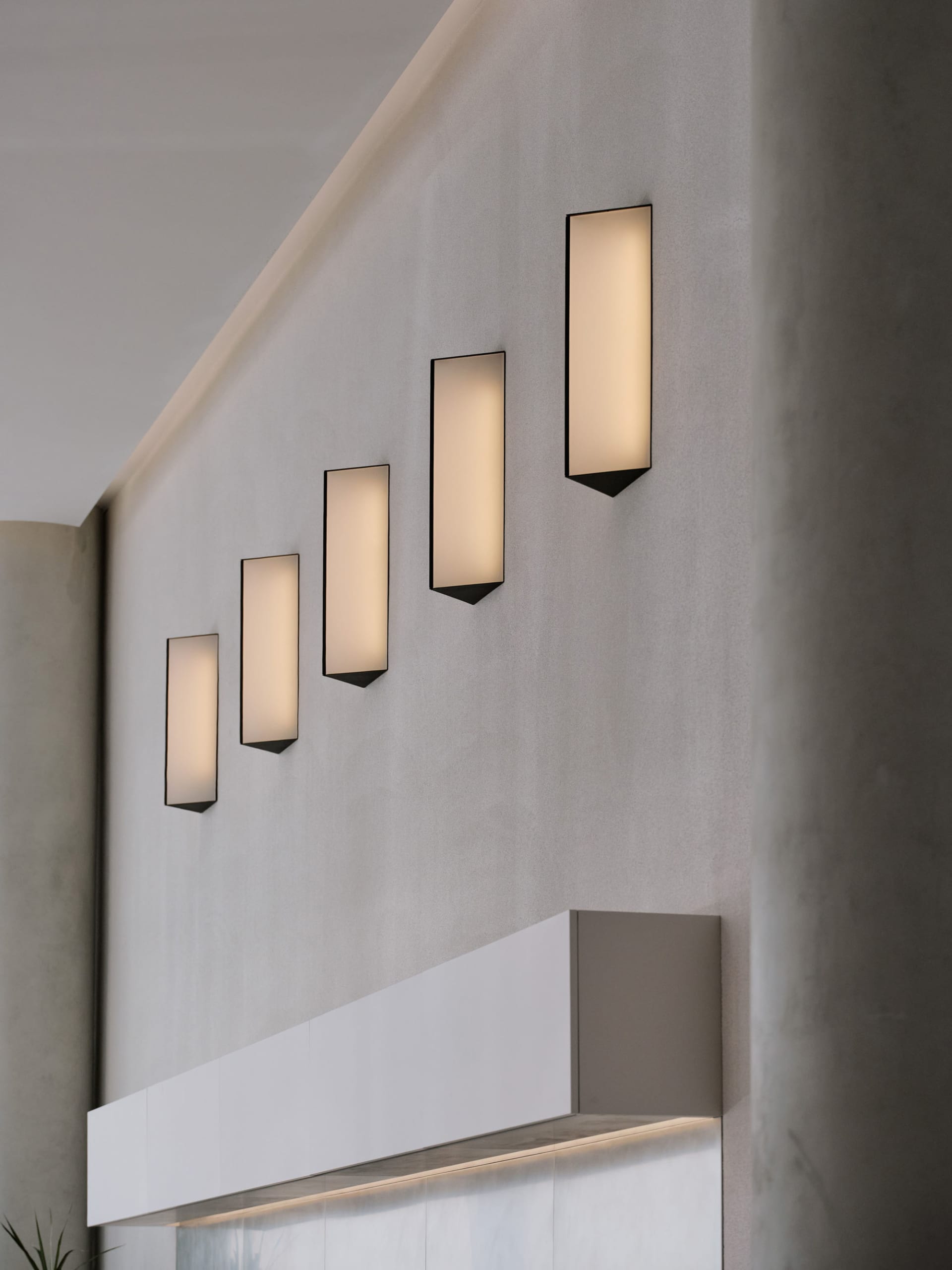 A concrete wall with five evenly spaced lights mounted along its length, creating a row of illuminated squares