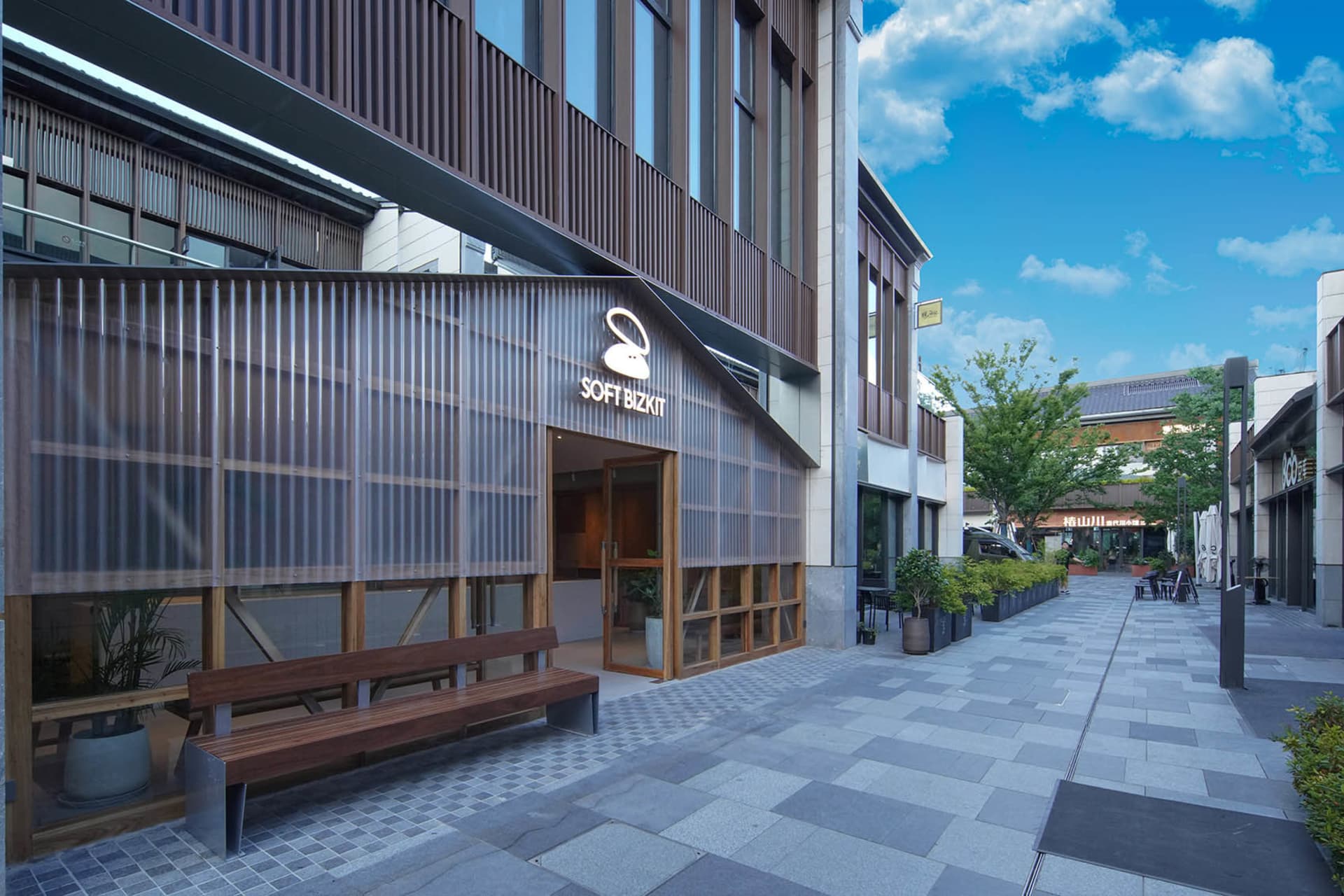 一座木造建築，擁有大型窗戶，門前擺放兩張木製長椅，置身於寧靜而溫馨的環境中