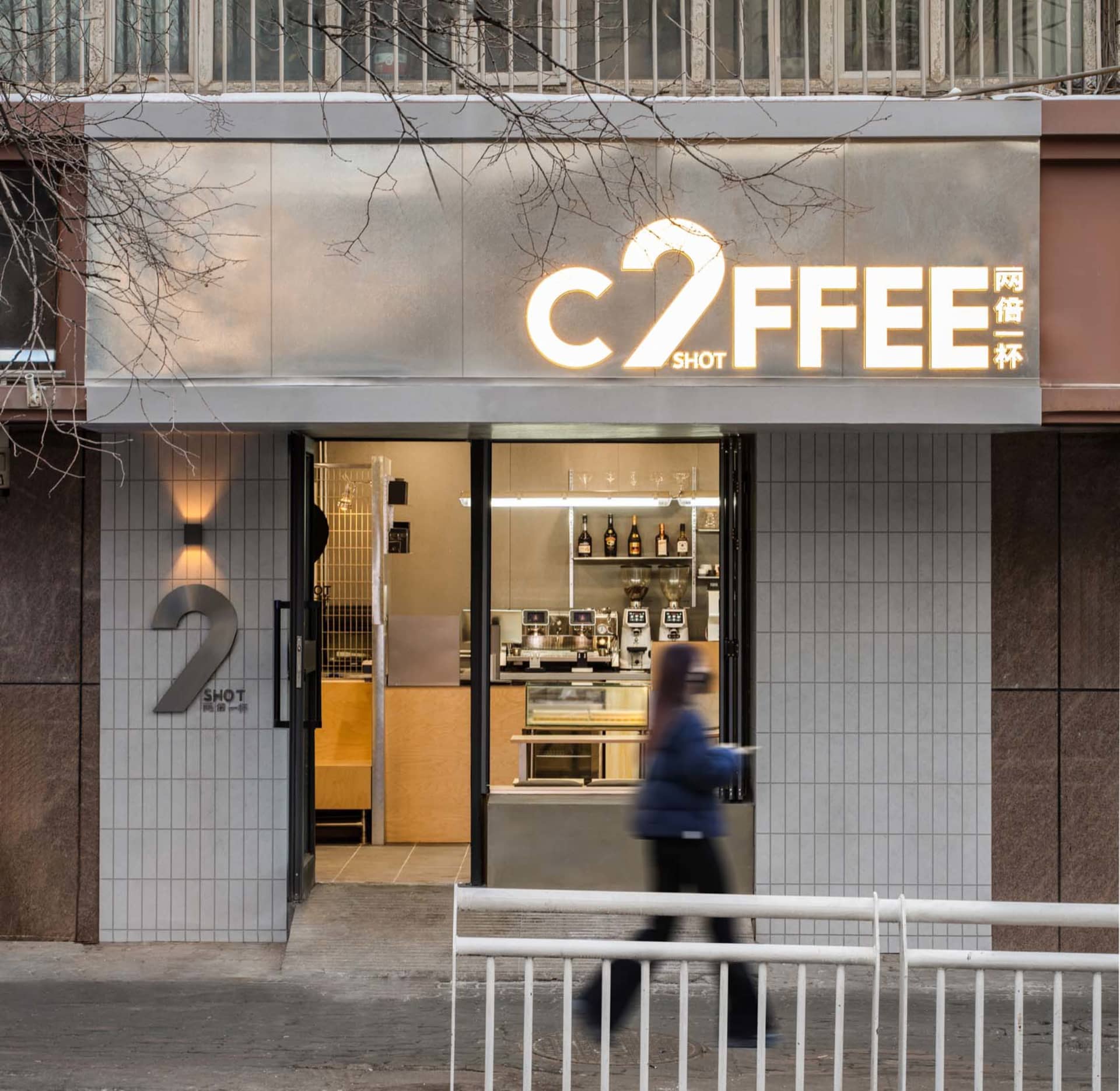 A casual Asian coffee shop with a woman walking past, featuring wooden accents and a welcoming atmosphere