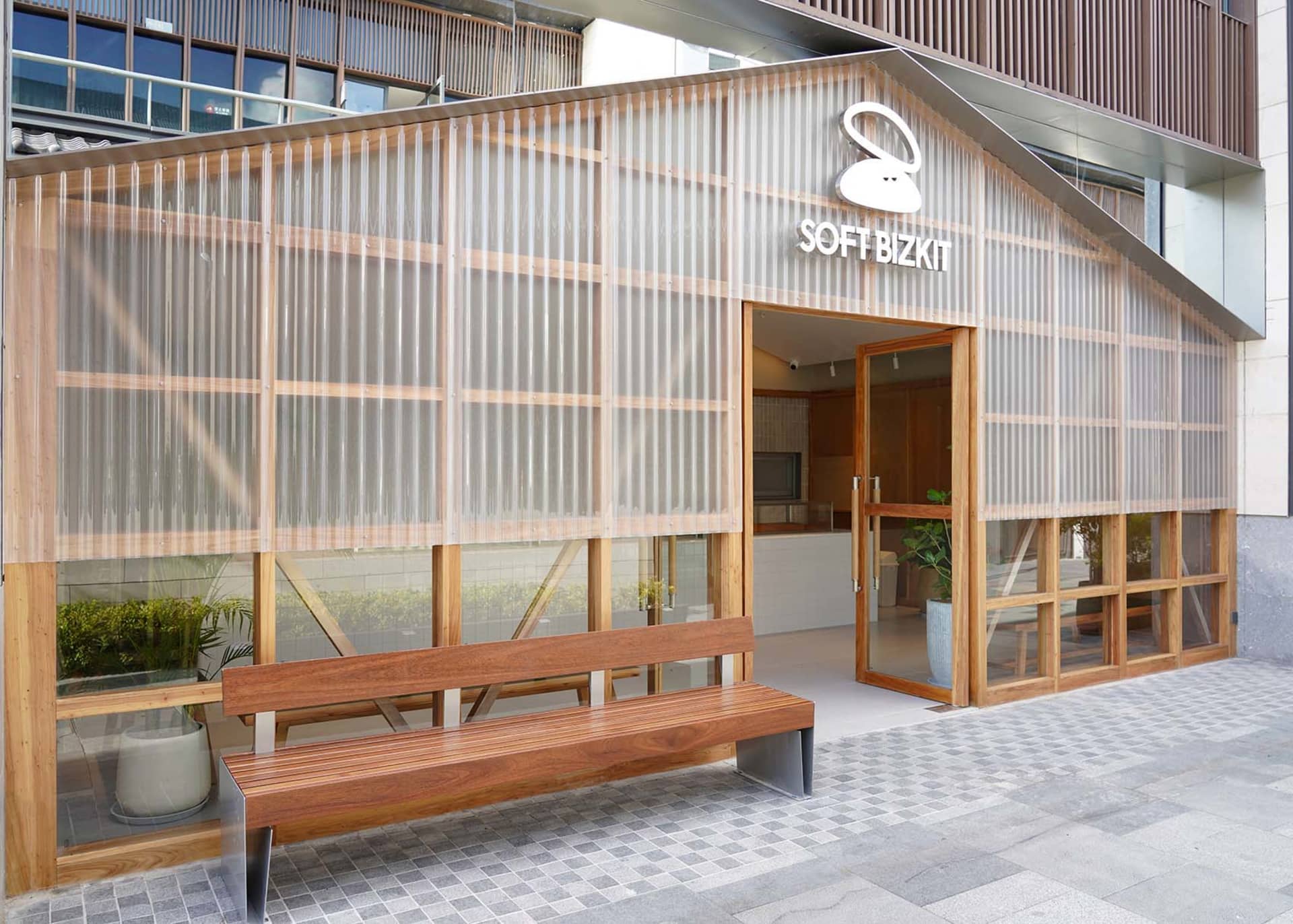 開放式客廳區域配有木製長椅、玻璃門、盆栽植物與水槽，營造溫暖親切的氛圍，融入自然元素