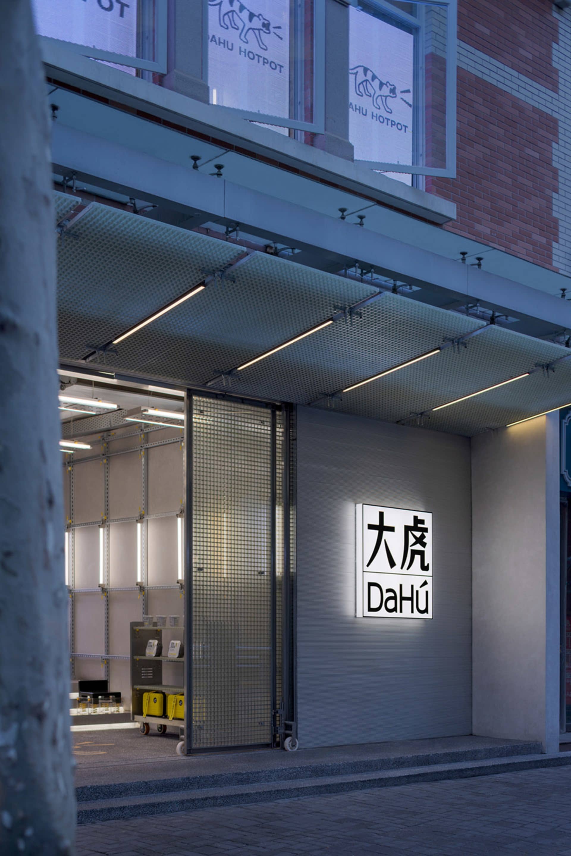A modern storefront with a large glass window, a metal frame, and a sign in front, well lit by natural light