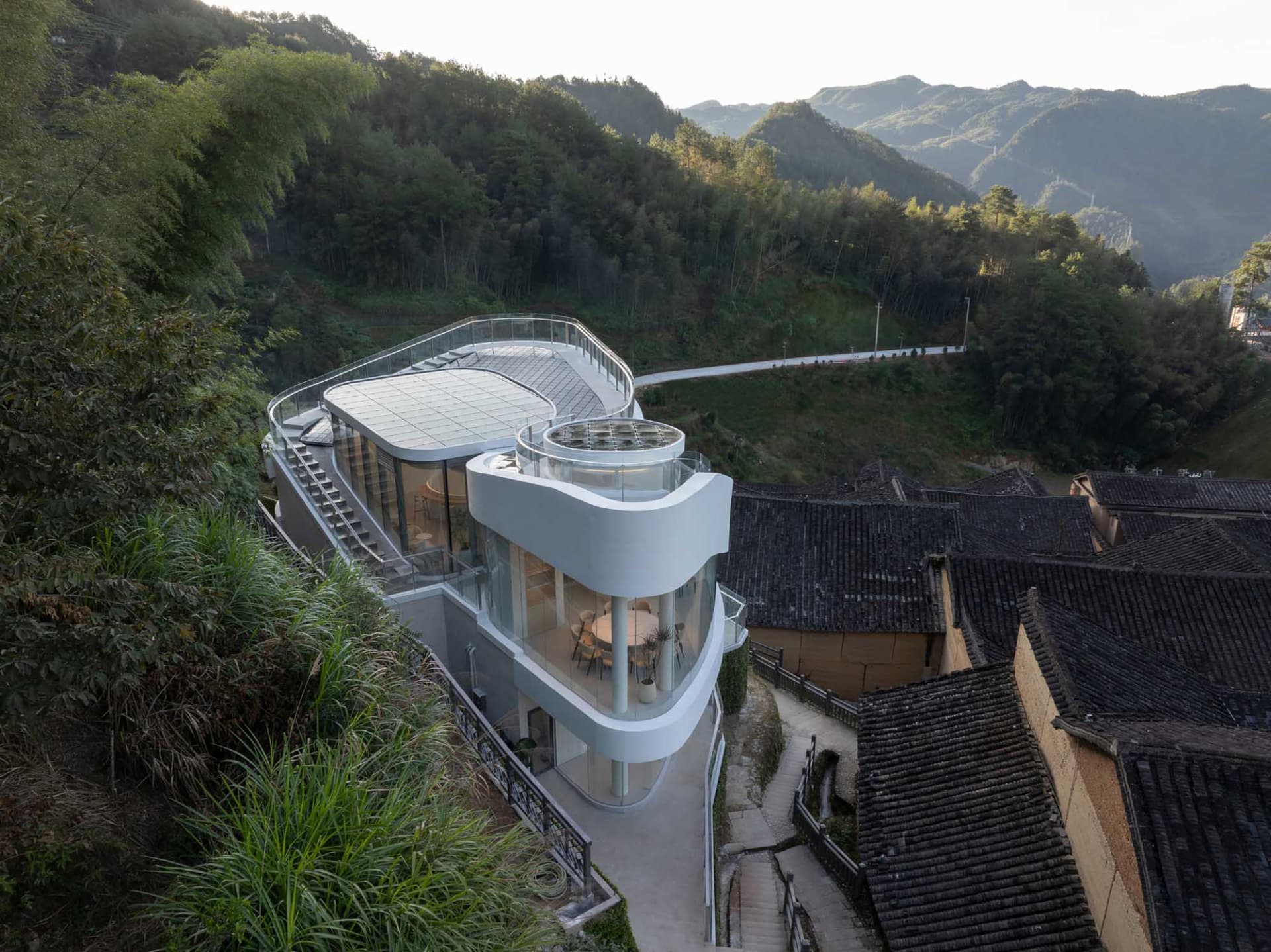 現代建築，弧形屋頂、玻璃牆面，位於山坡俯瞰谷地